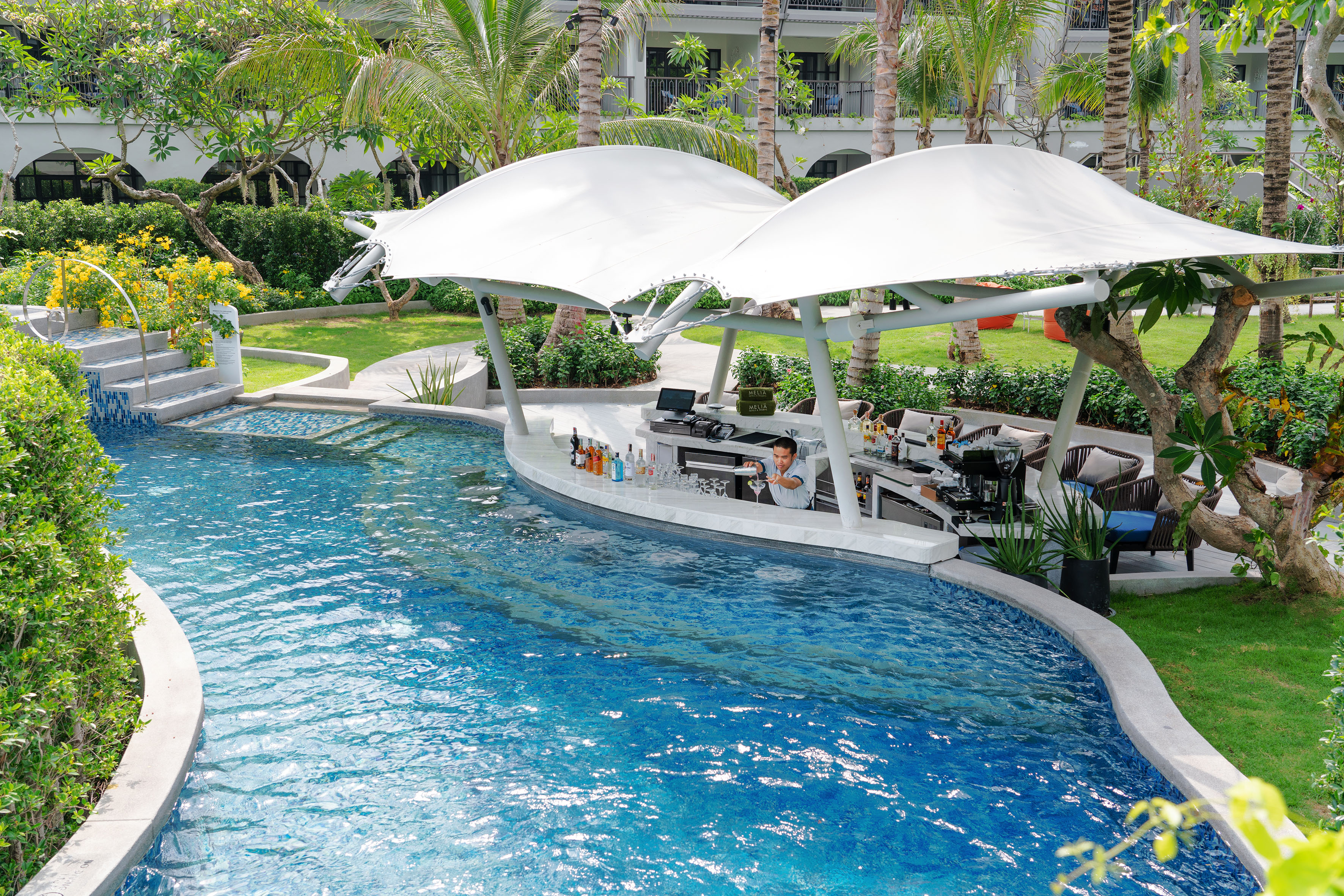 Luxury resort swim-up bar with bartender in tropical pool.