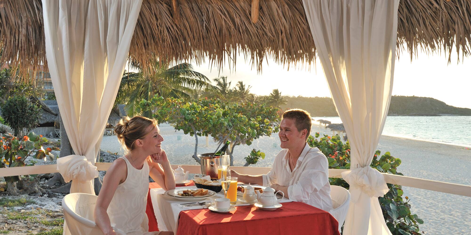 a man and woman sitting at a table with food and drinks