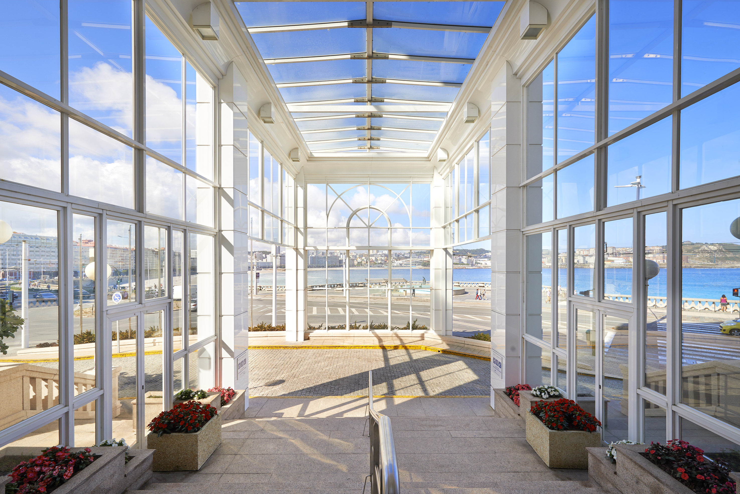 a glass building with a view of the water and a beach