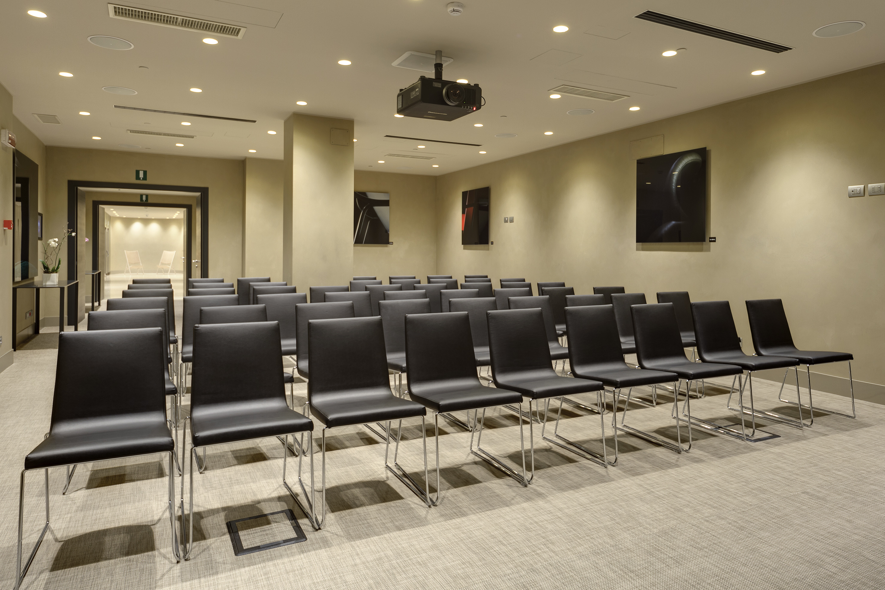 Modern meeting room with black chairs and ceiling projector.