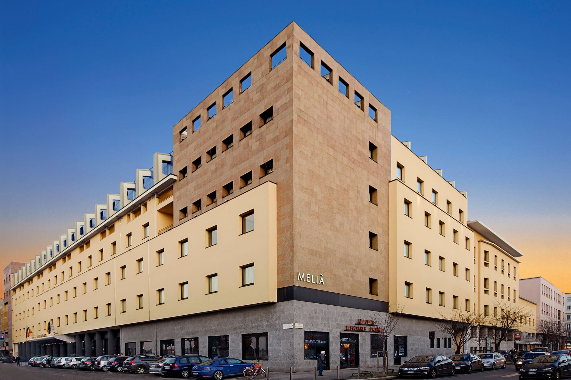 Melia hotel building with modern light yellow and stone exterior on city street.