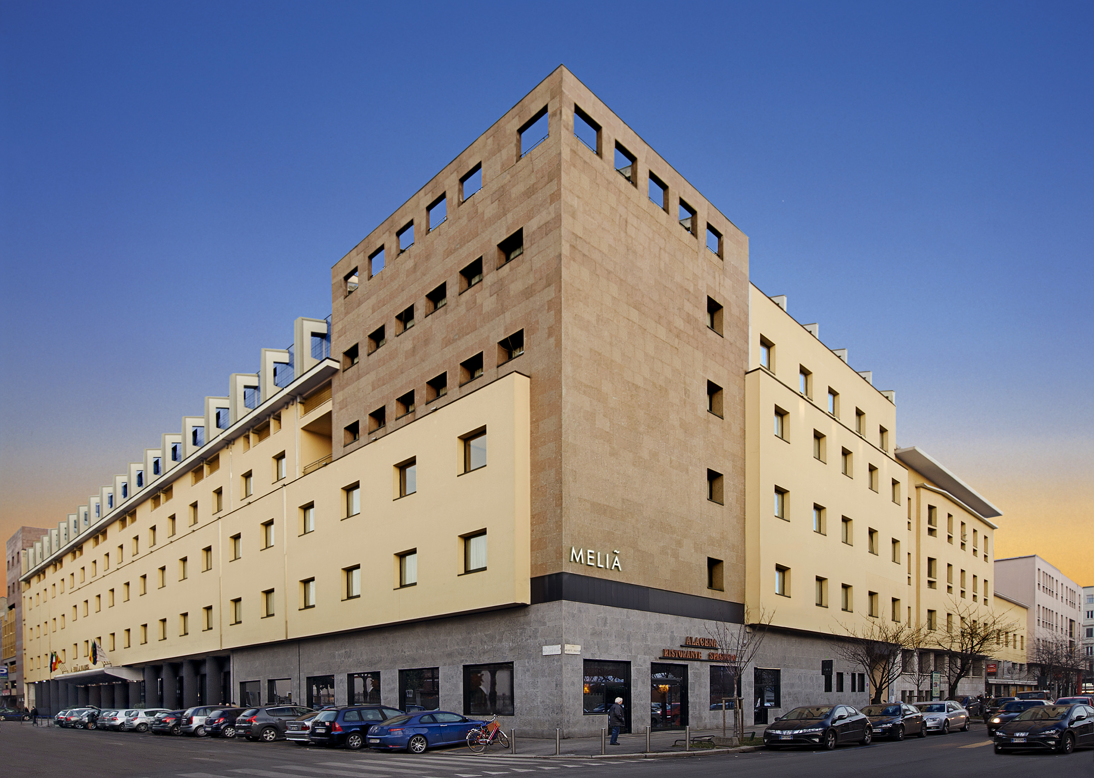 Melia hotel building with modern light yellow and stone exterior on city street.