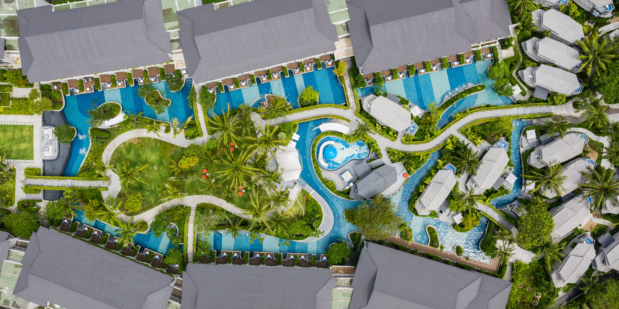 a aerial view of a resort with swimming pools and trees