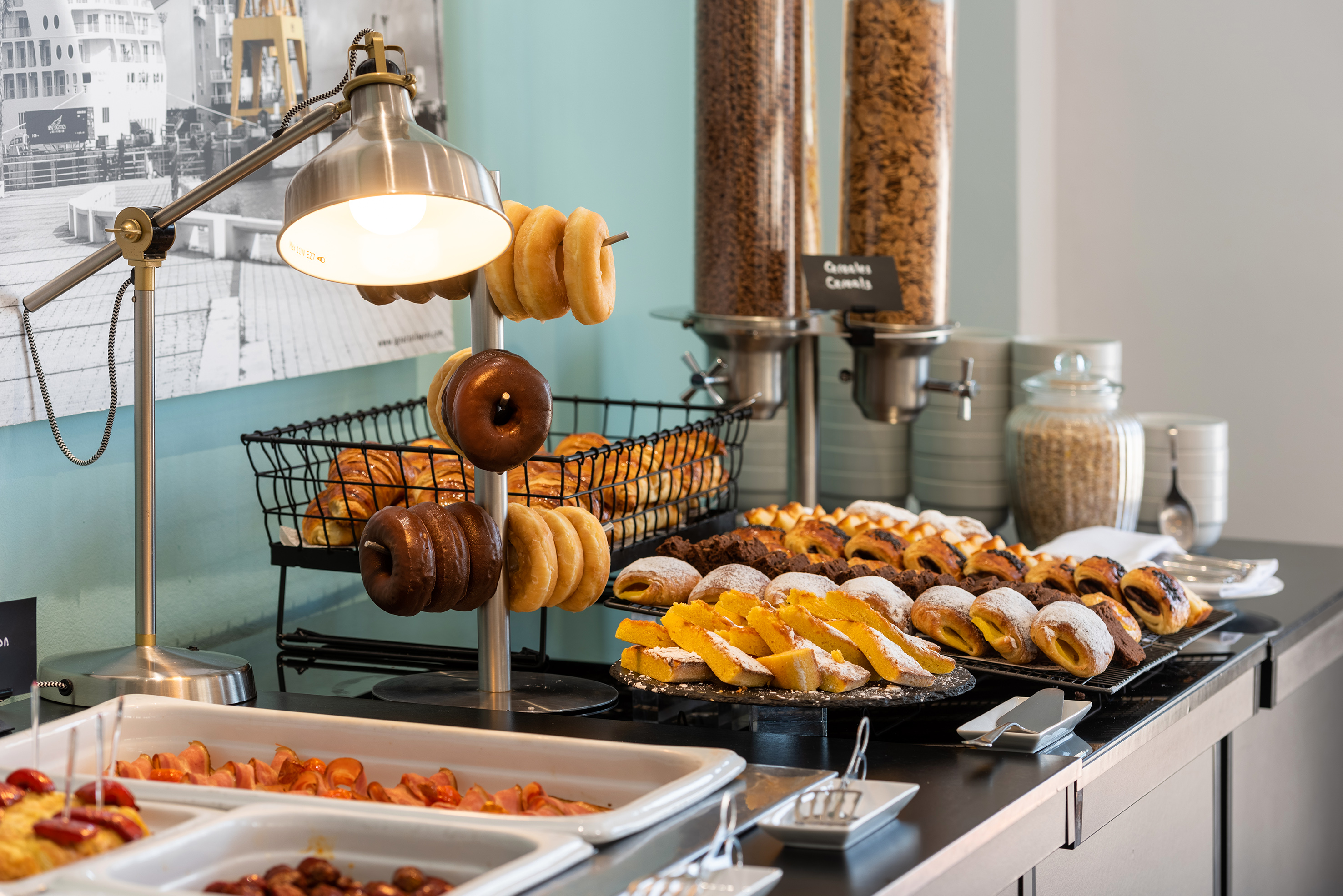 Continental breakfast buffet with pastries, donuts, cereal, and hot food.