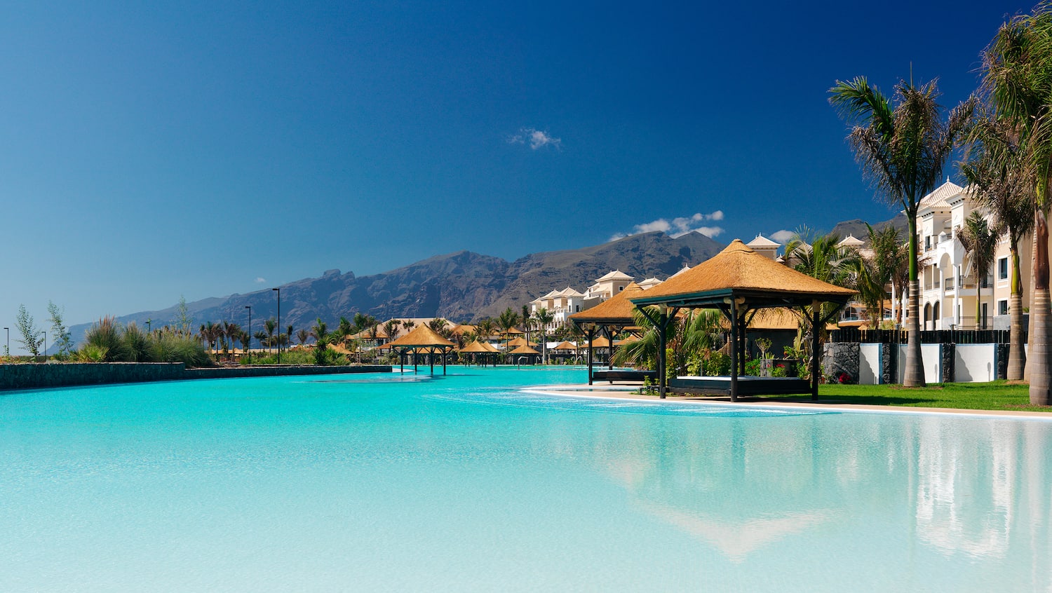 a pool with a building and a mountain in the background