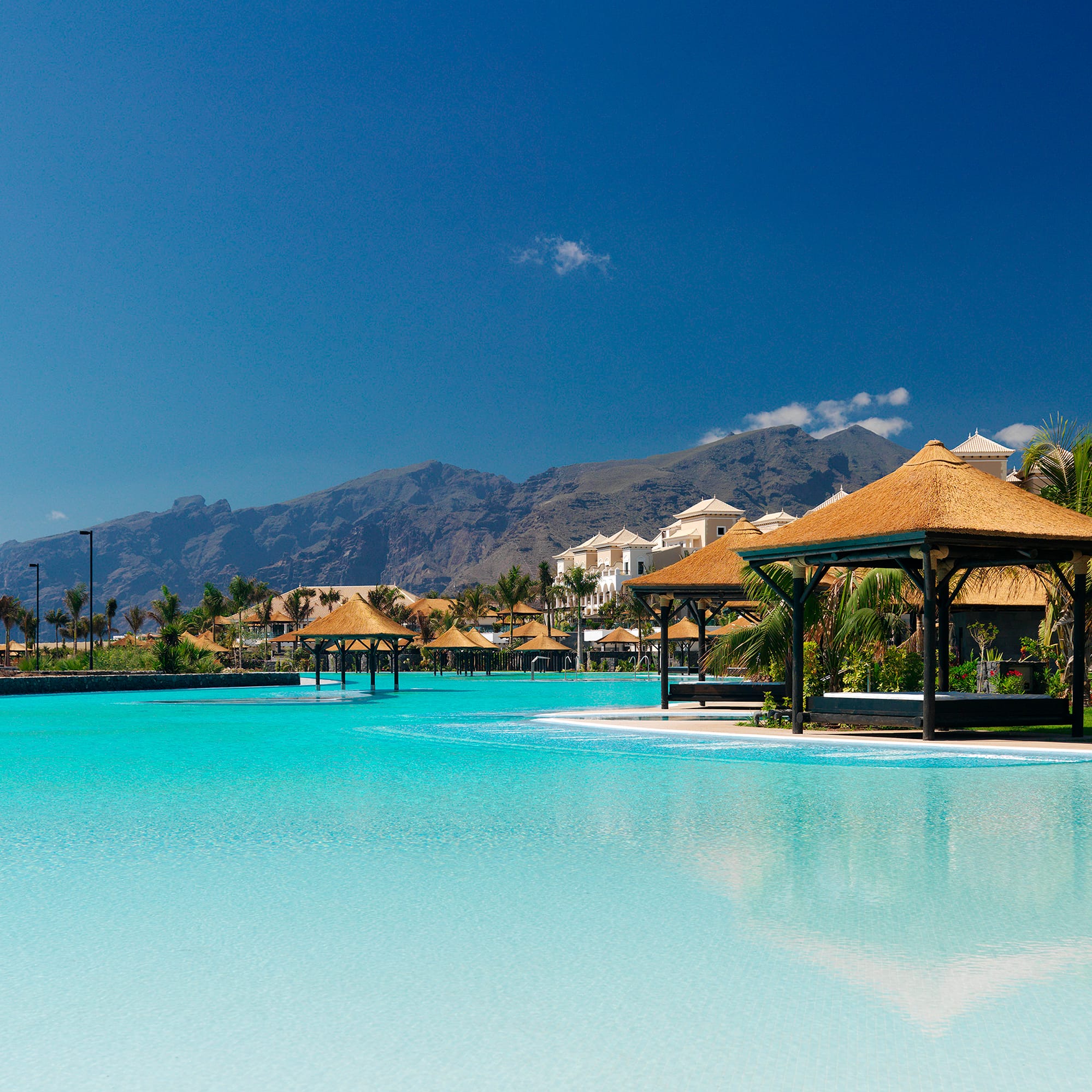 a pool with a building and a mountain in the background