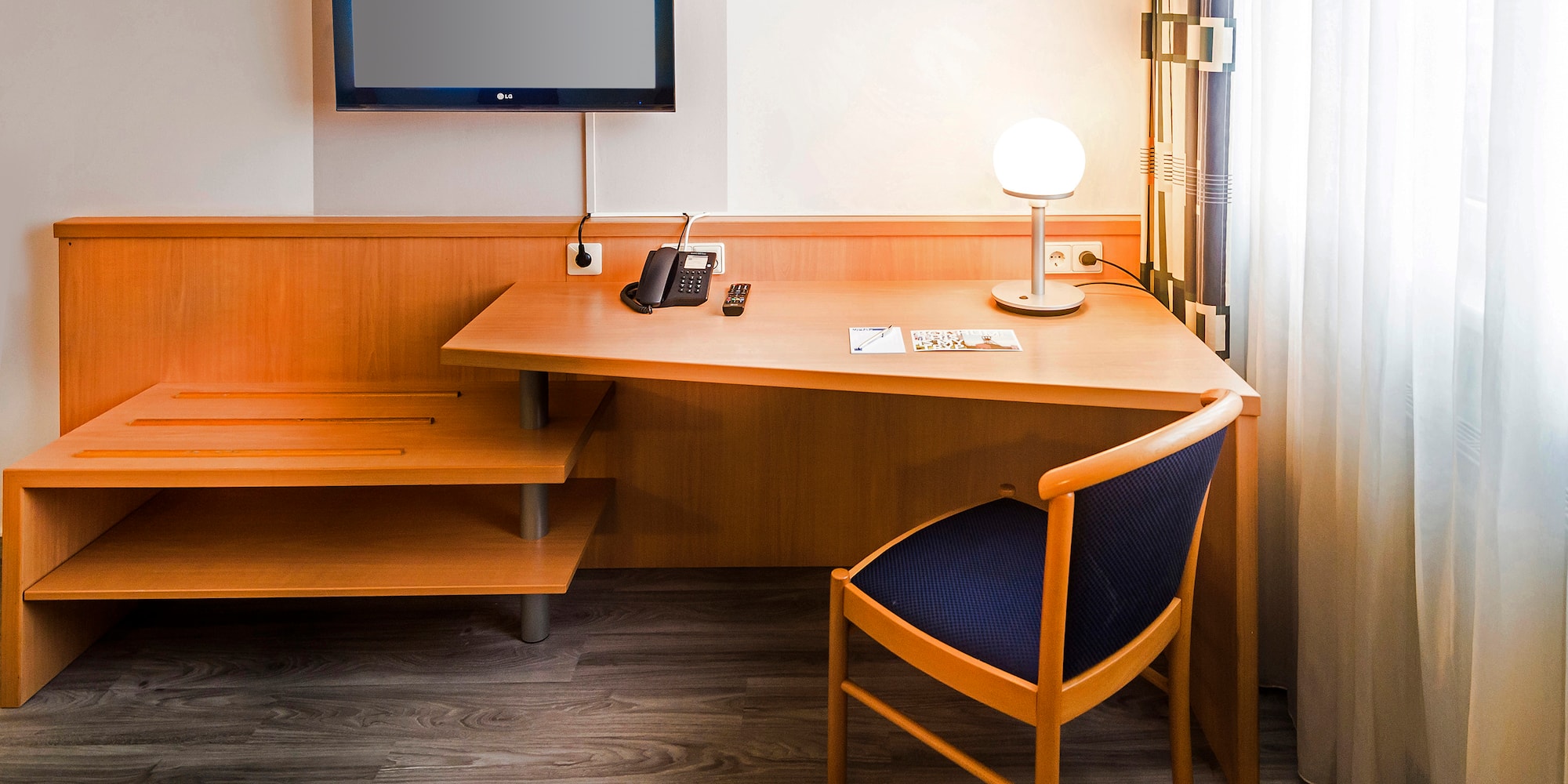 a desk with a chair and a television on the wall