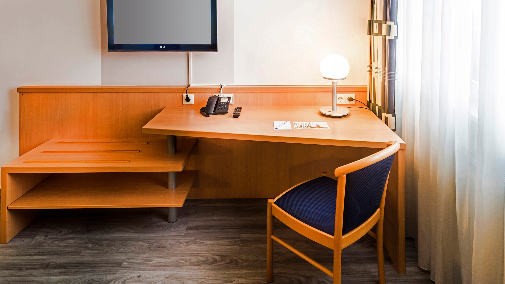 a desk with a chair and a television on the wall