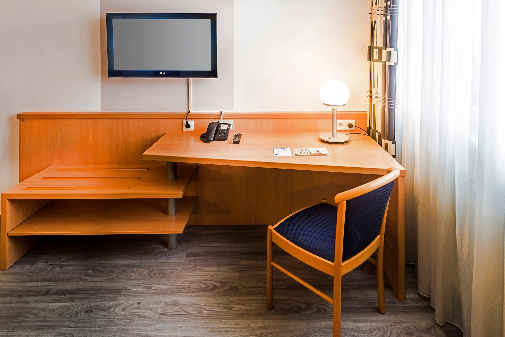 a desk with a chair and a television on the wall