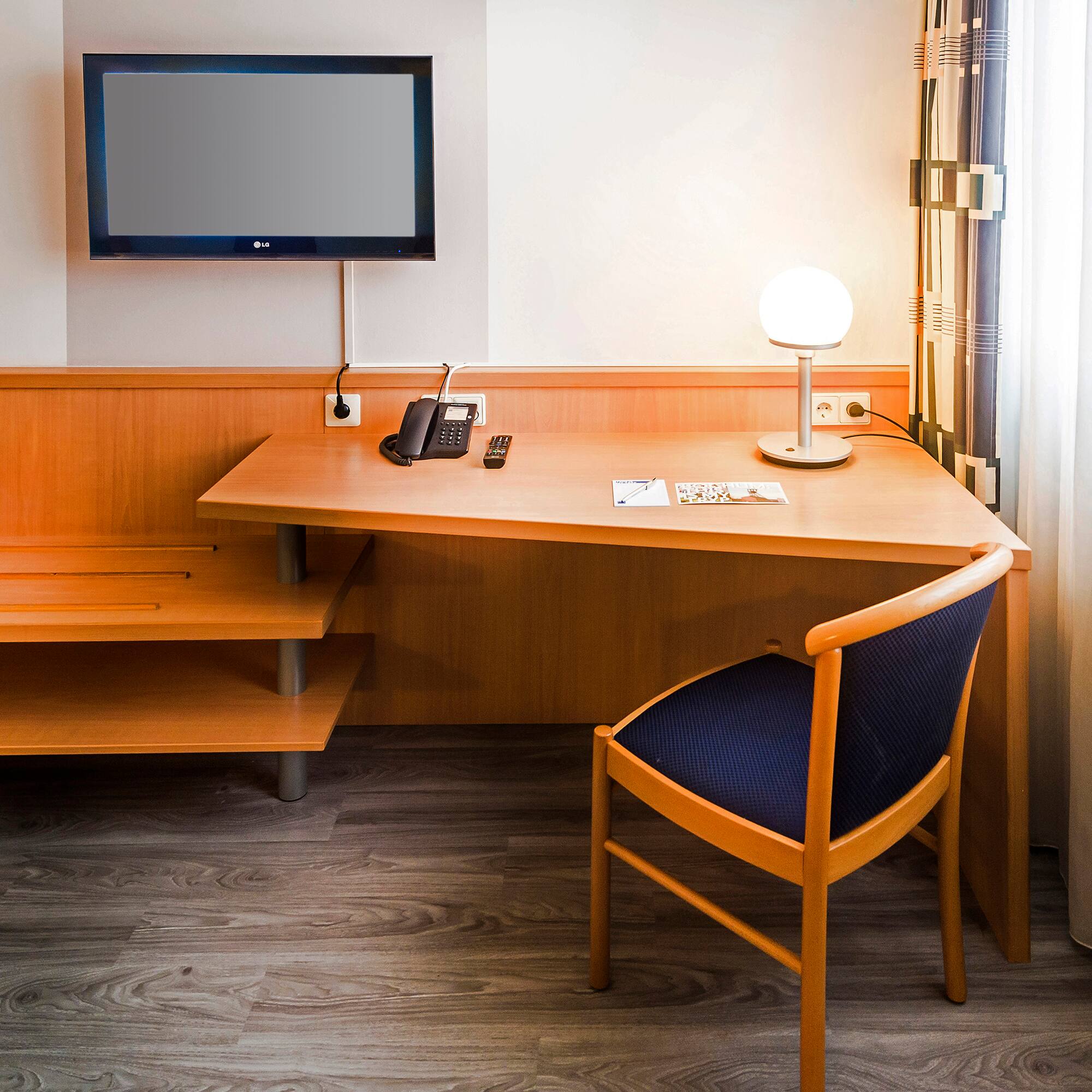 a desk with a chair and a television on the wall