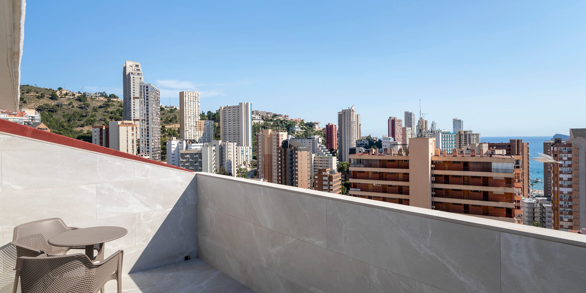 a table and chair on a rooftop overlooking a city