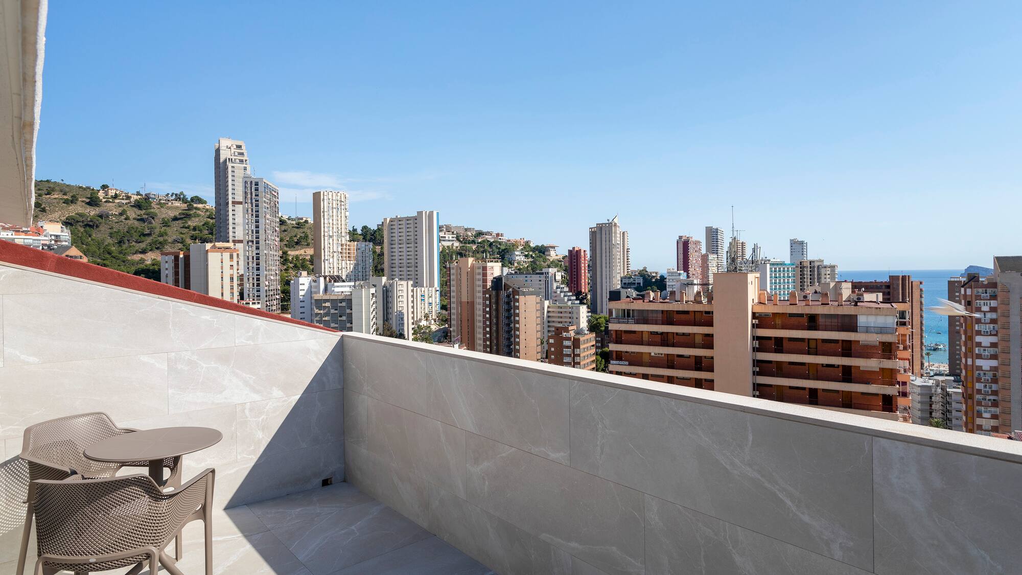 a table and chair on a rooftop overlooking a city