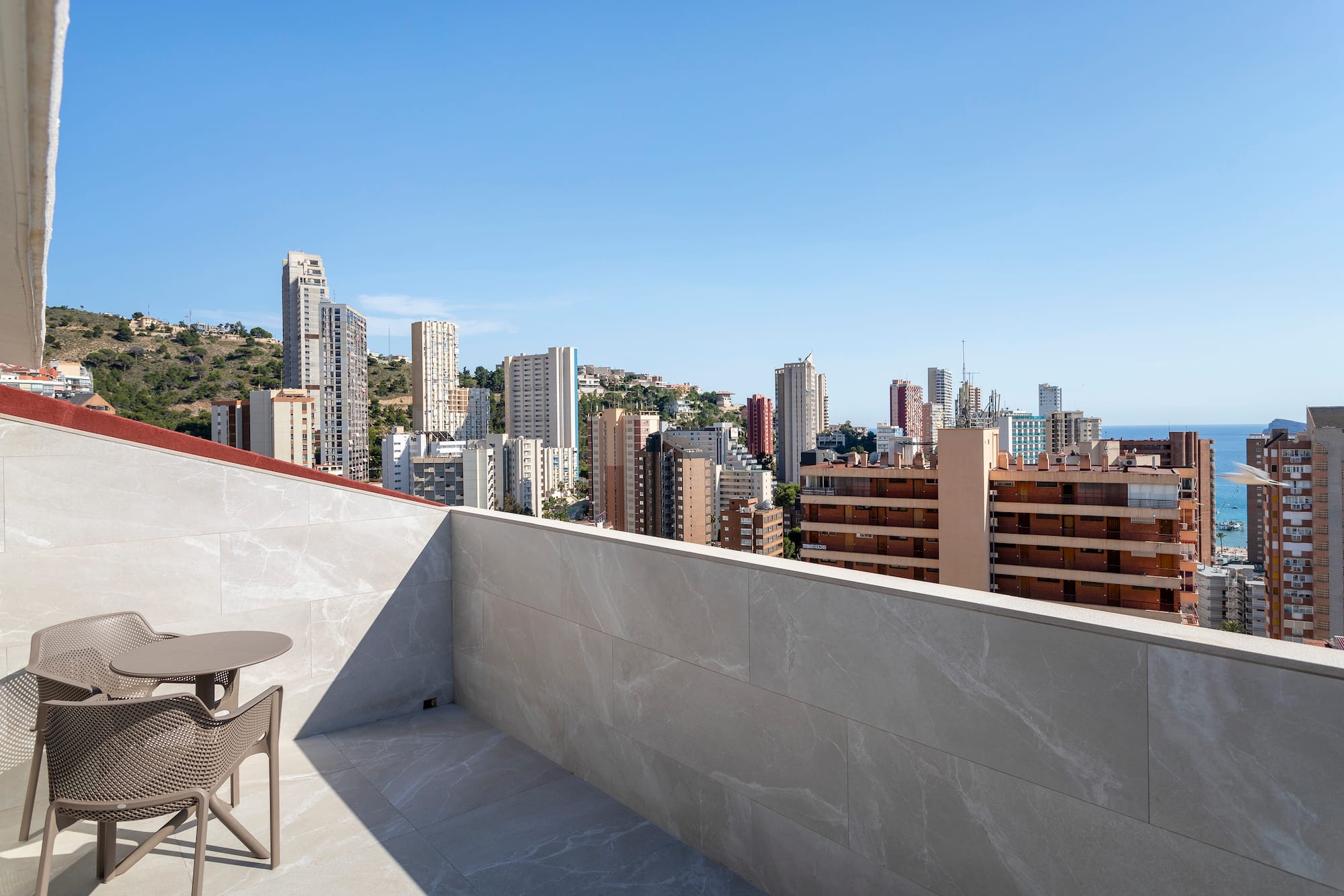 a table and chair on a rooftop overlooking a city