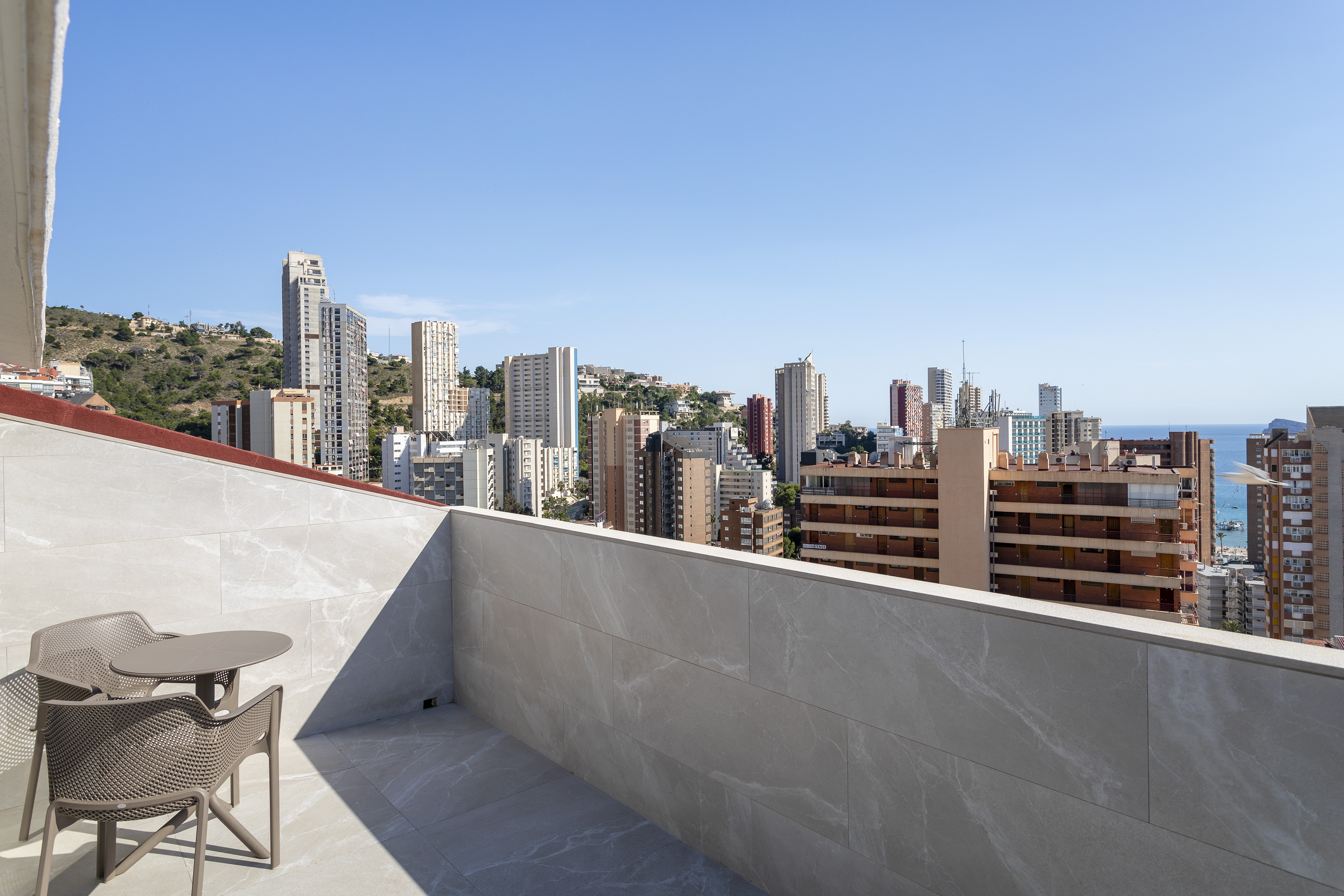 a table and chair on a rooftop overlooking a city
