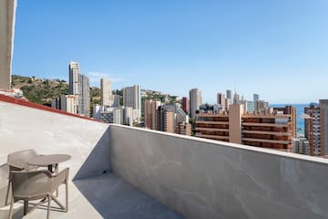 a table and chair on a rooftop overlooking a city
