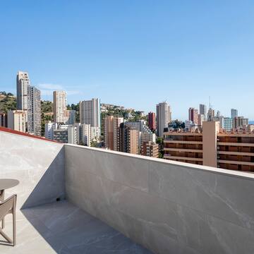 a table and chair on a rooftop overlooking a city