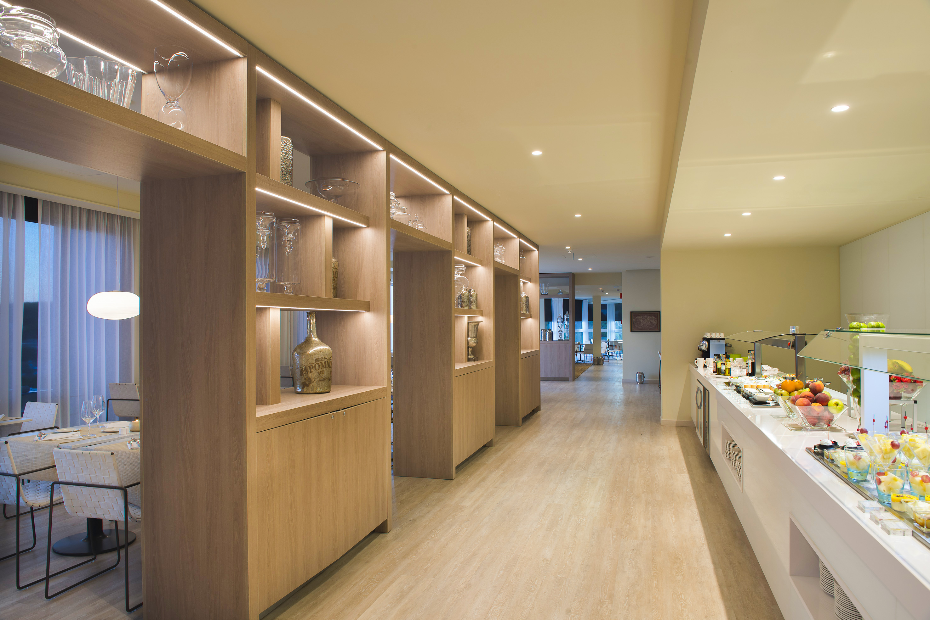 Modern hotel restaurant buffet with illuminated wooden display shelves.