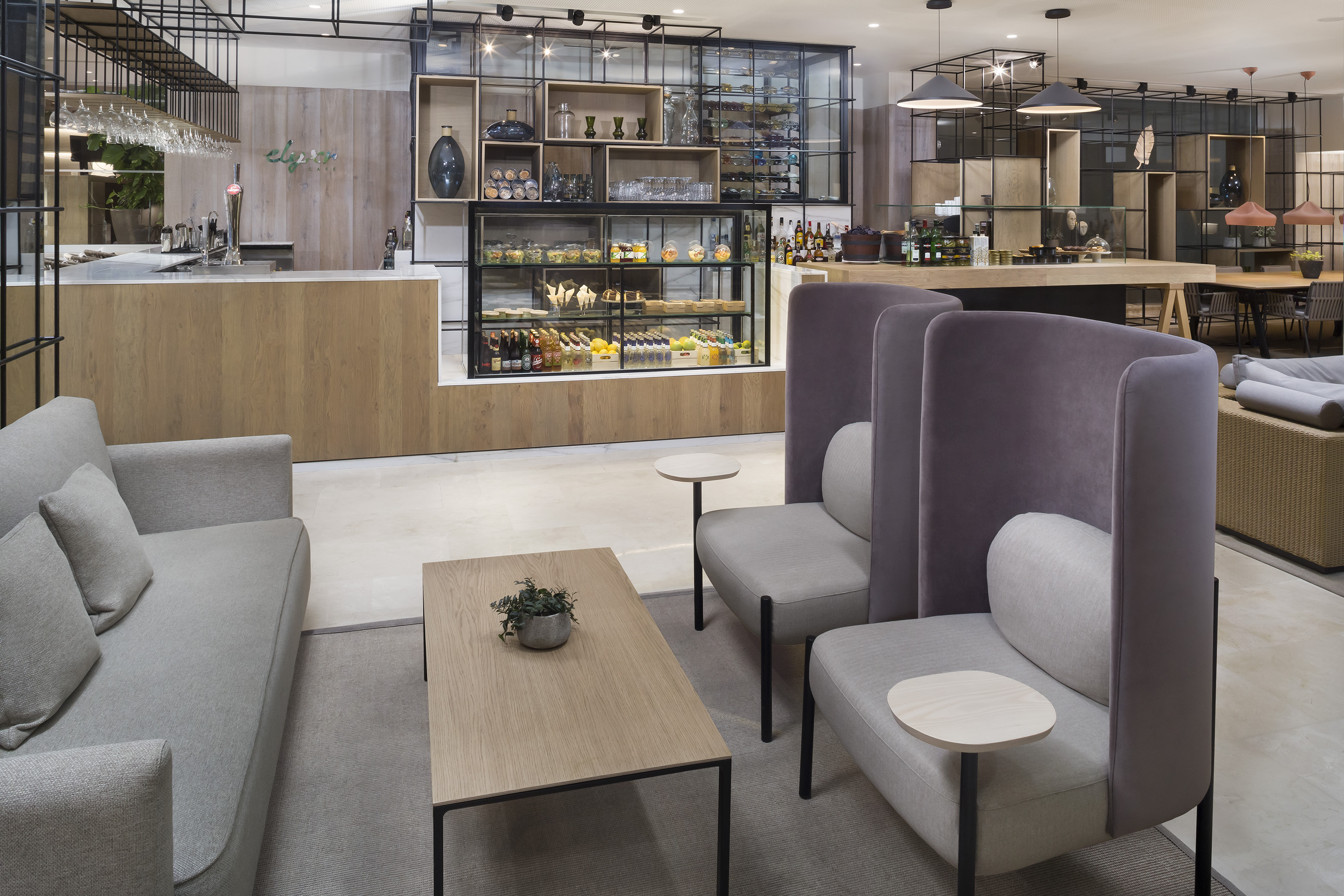 Modern hotel lobby/cafe with stylish bar, comfortable seating, and food display.