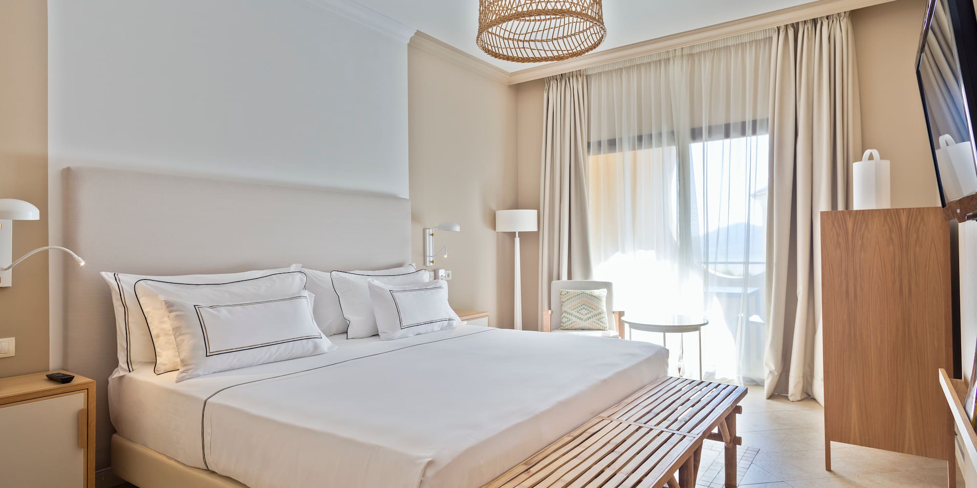 a bed with a bench and a lamp from the ceiling