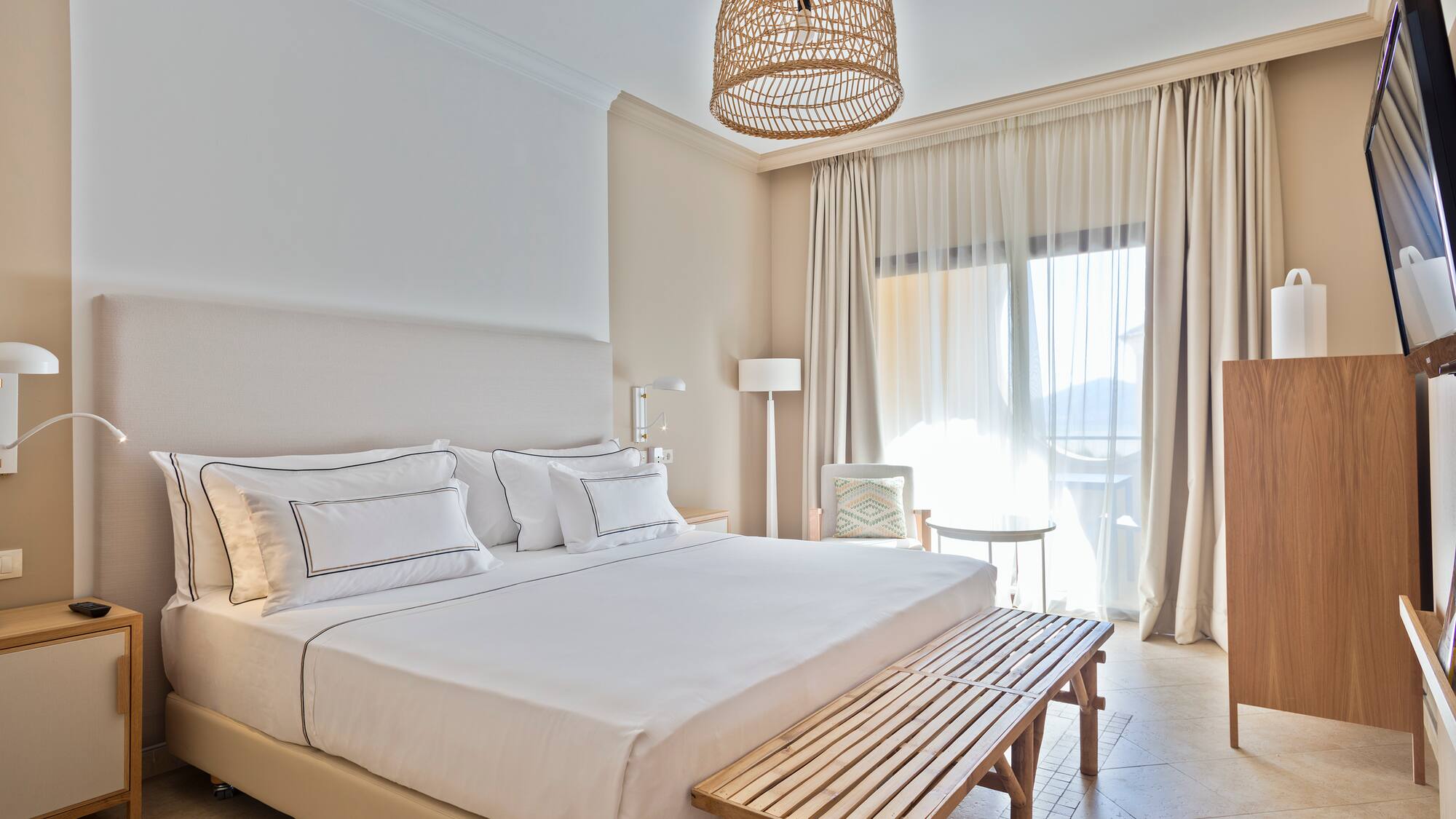 a bed with a bench and a lamp from the ceiling