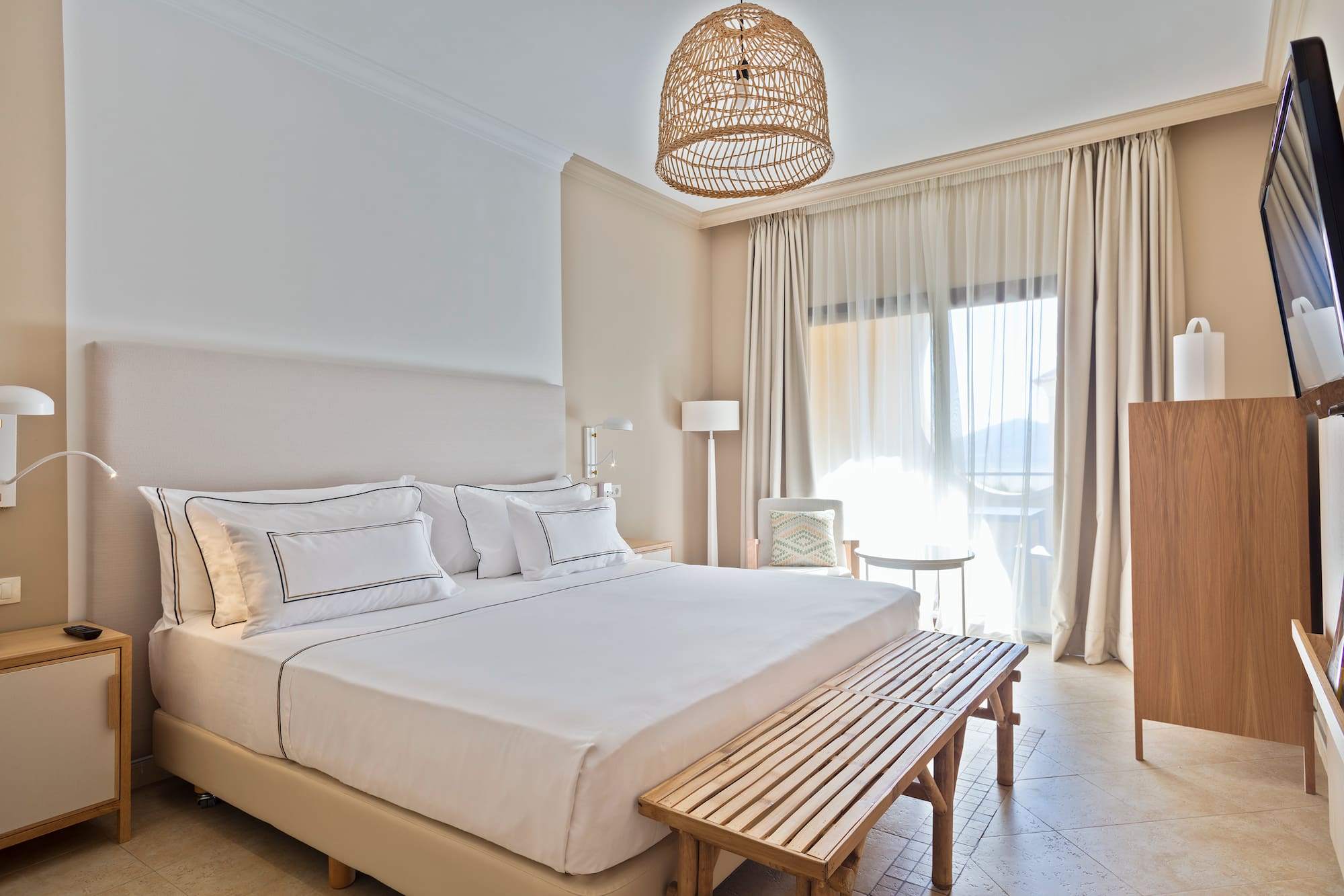 a bed with a bench and a lamp from the ceiling