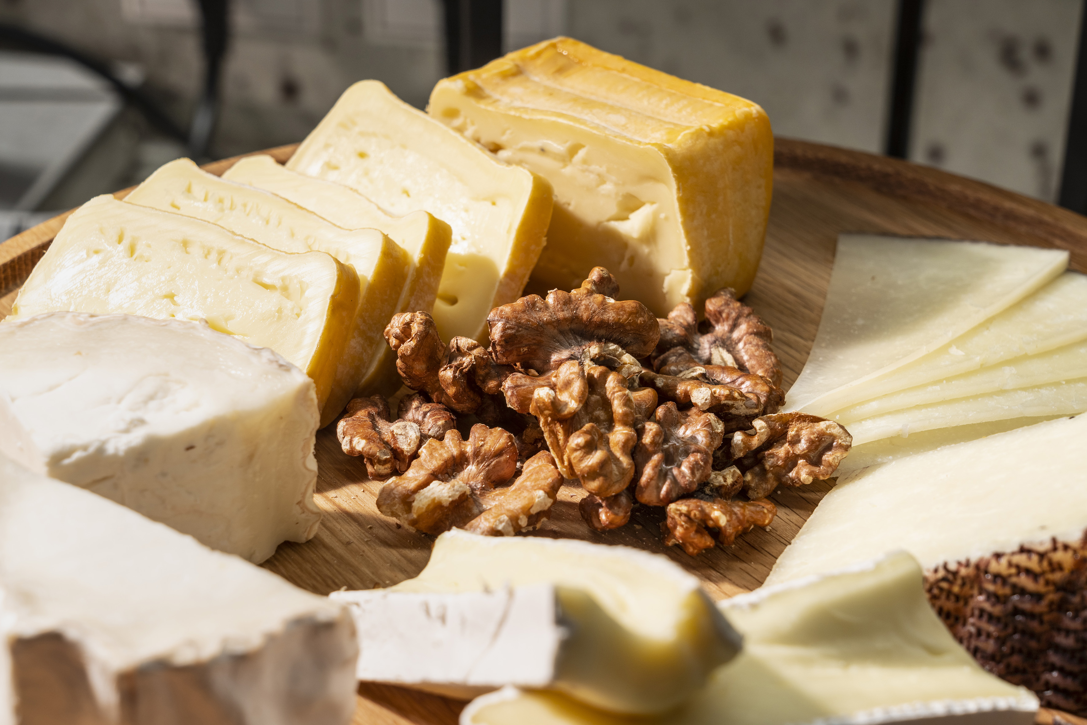 Wooden cheese board with an assortment of cheeses and walnuts.