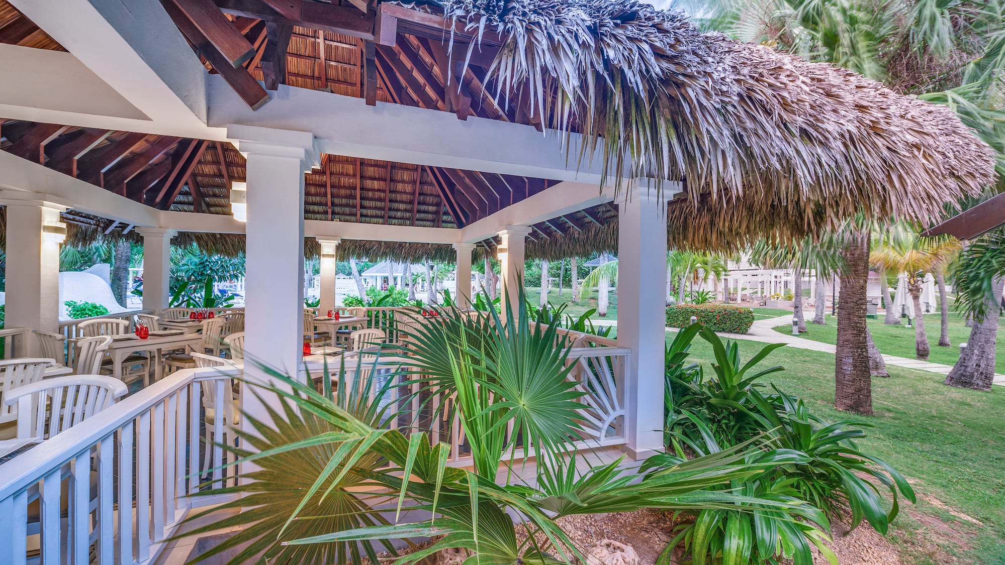 a gazebo with palm trees and grass