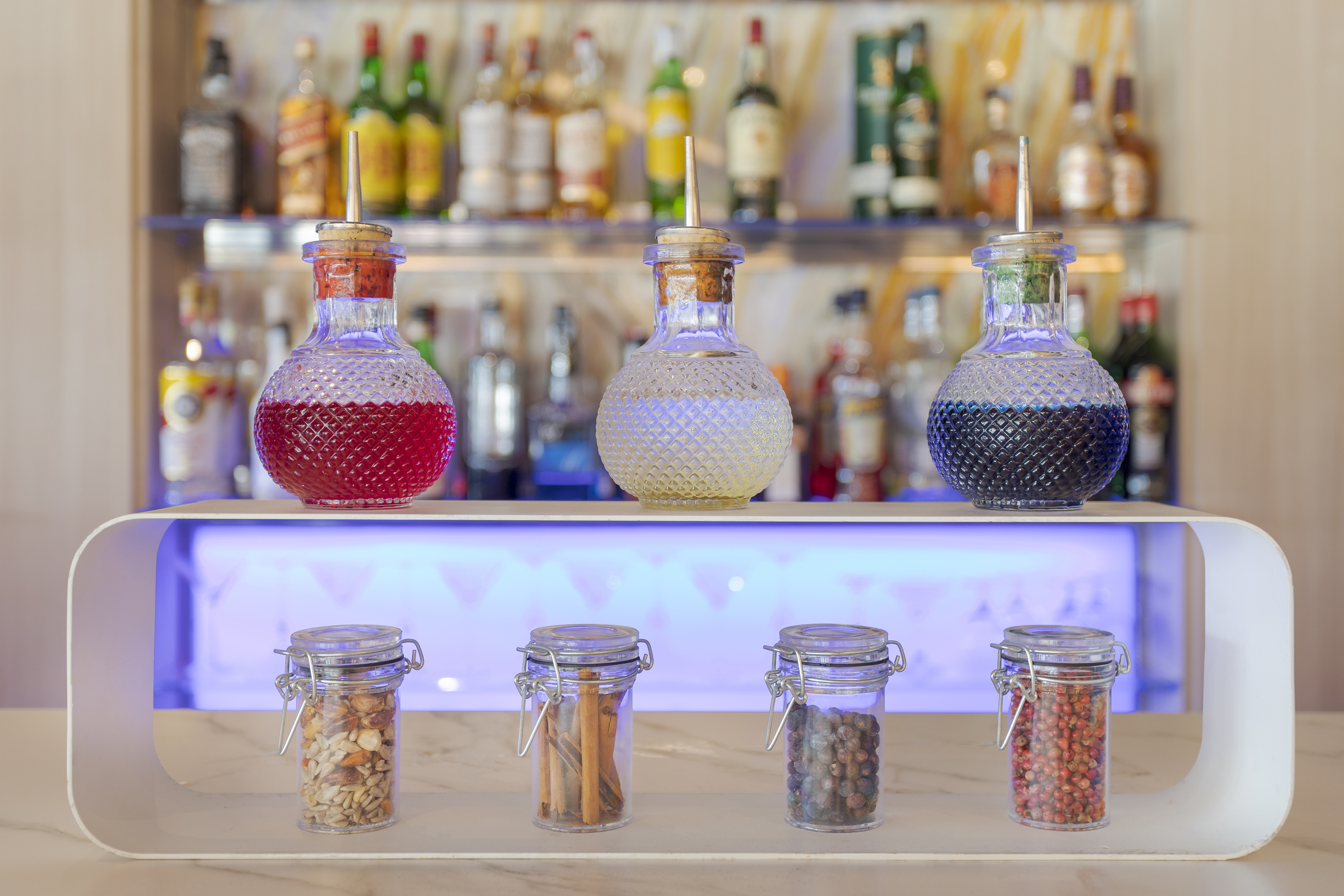 Colorful bar syrups, nuts, cinnamon, and peppercorns for cocktails.