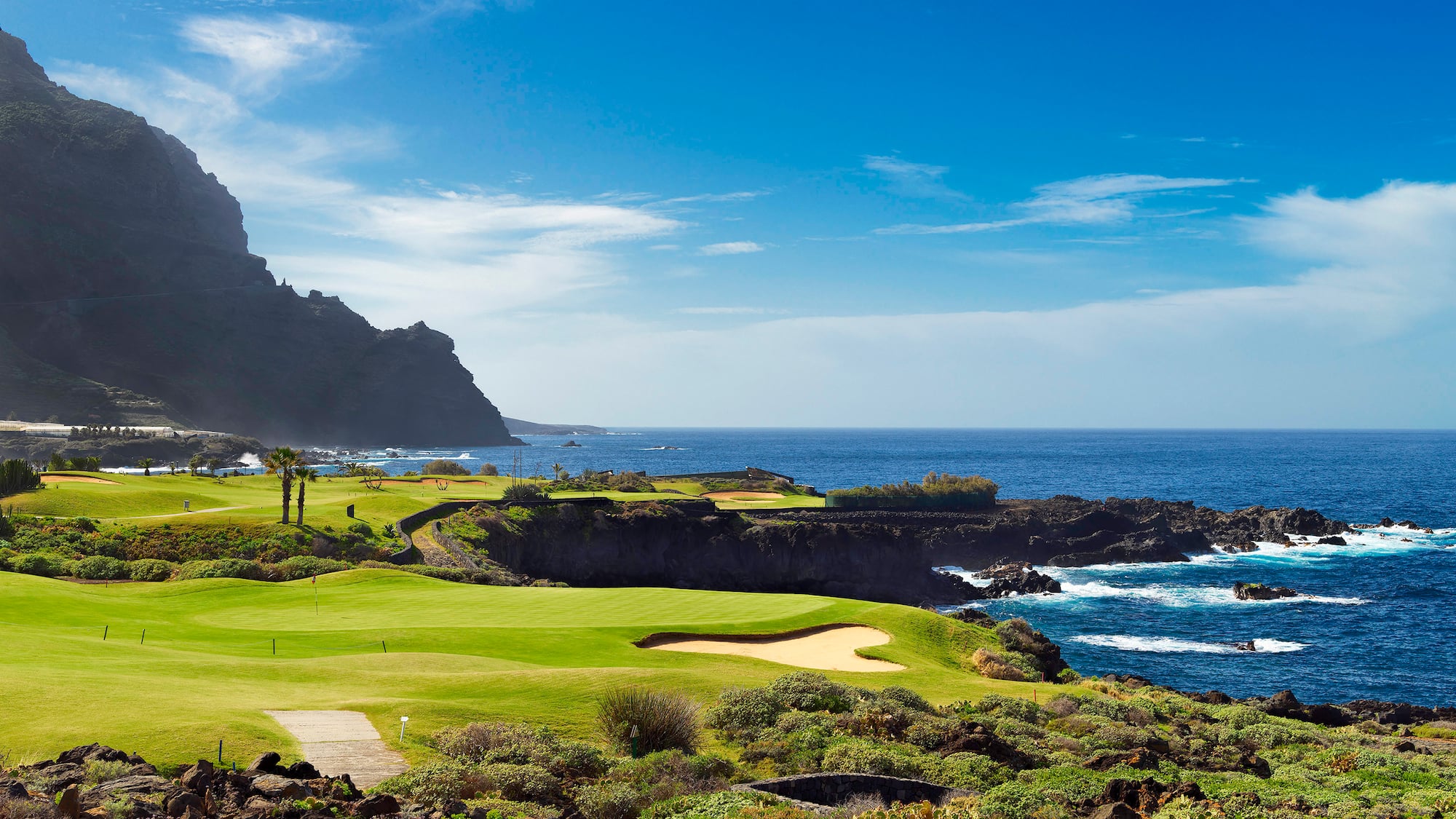 a golf course with a body of water and a hill