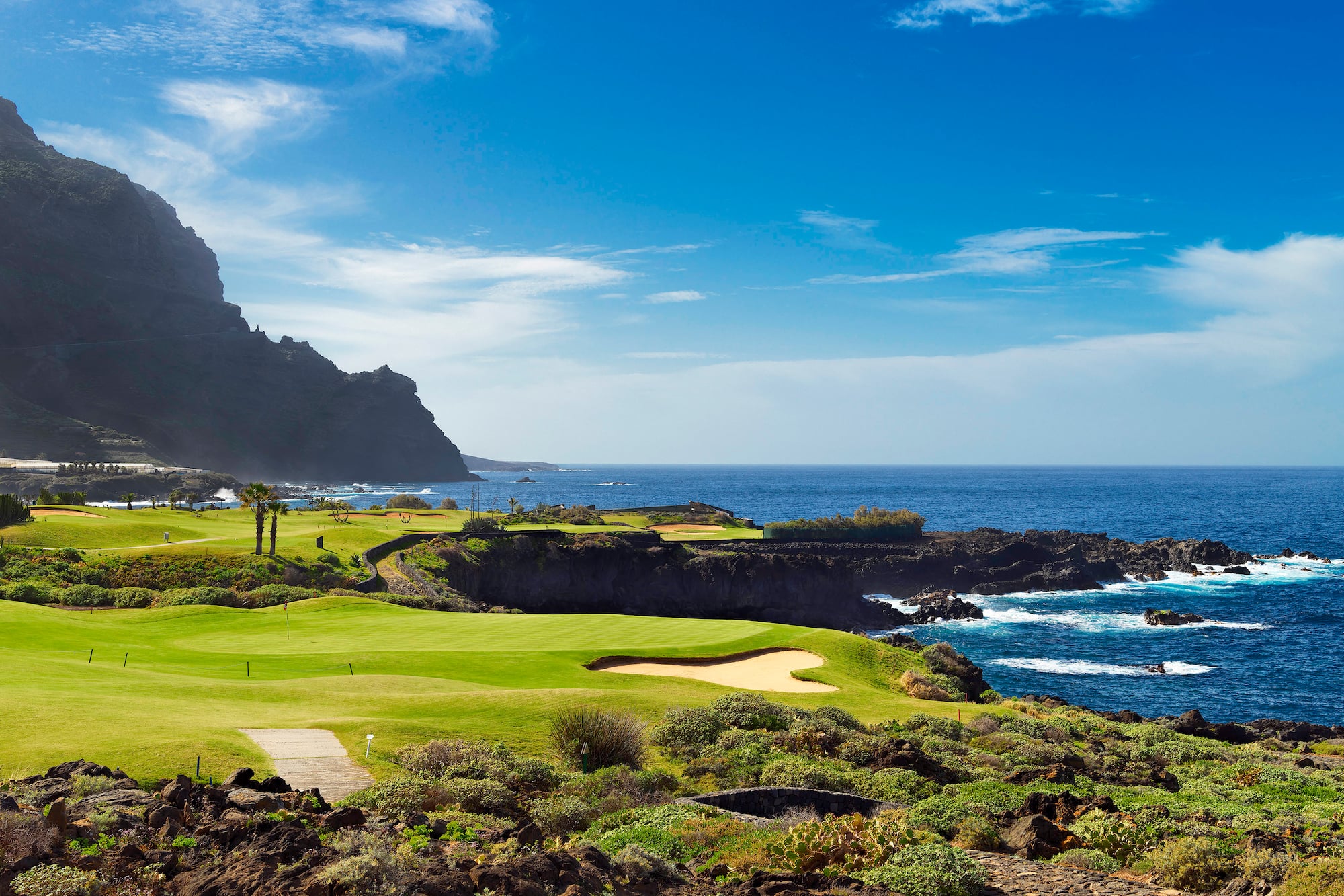 a golf course with a body of water and a hill