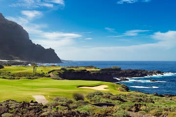 a golf course with a body of water and a hill