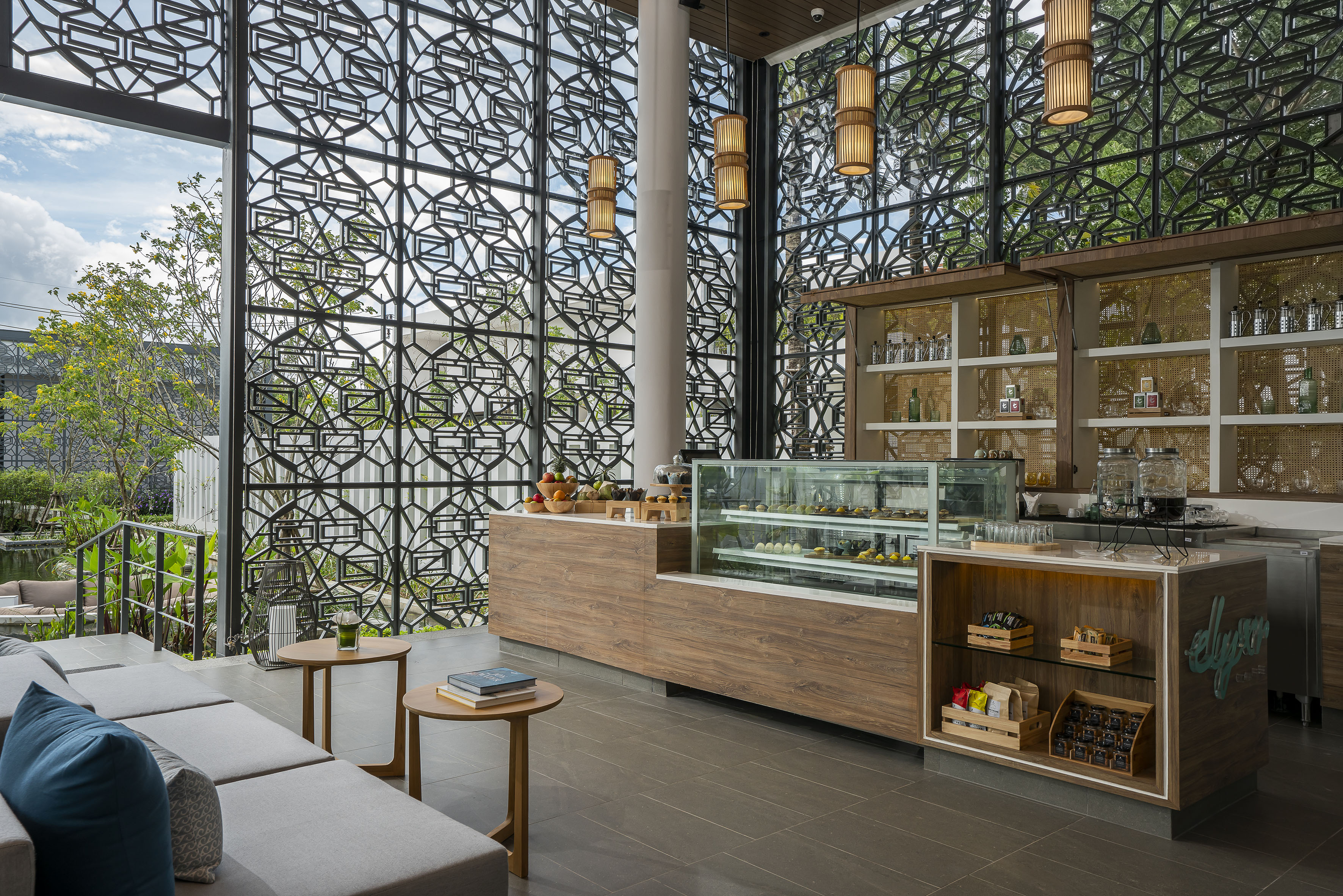 Modern cafe lounge with geometric screen walls and dessert counter.