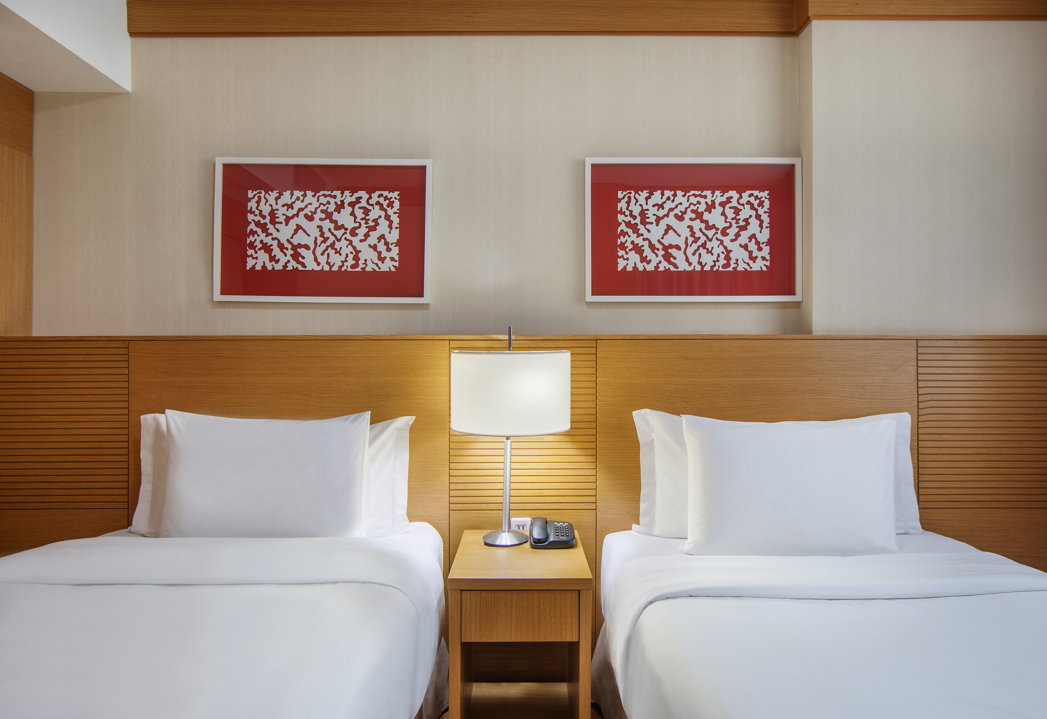 Hotel room with two twin beds, wooden headboard, and red abstract art.