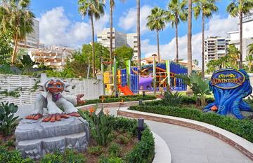 a playground with palm trees and a statue of a monkey