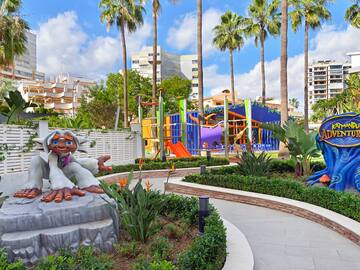 a playground with palm trees and a statue of a monkey