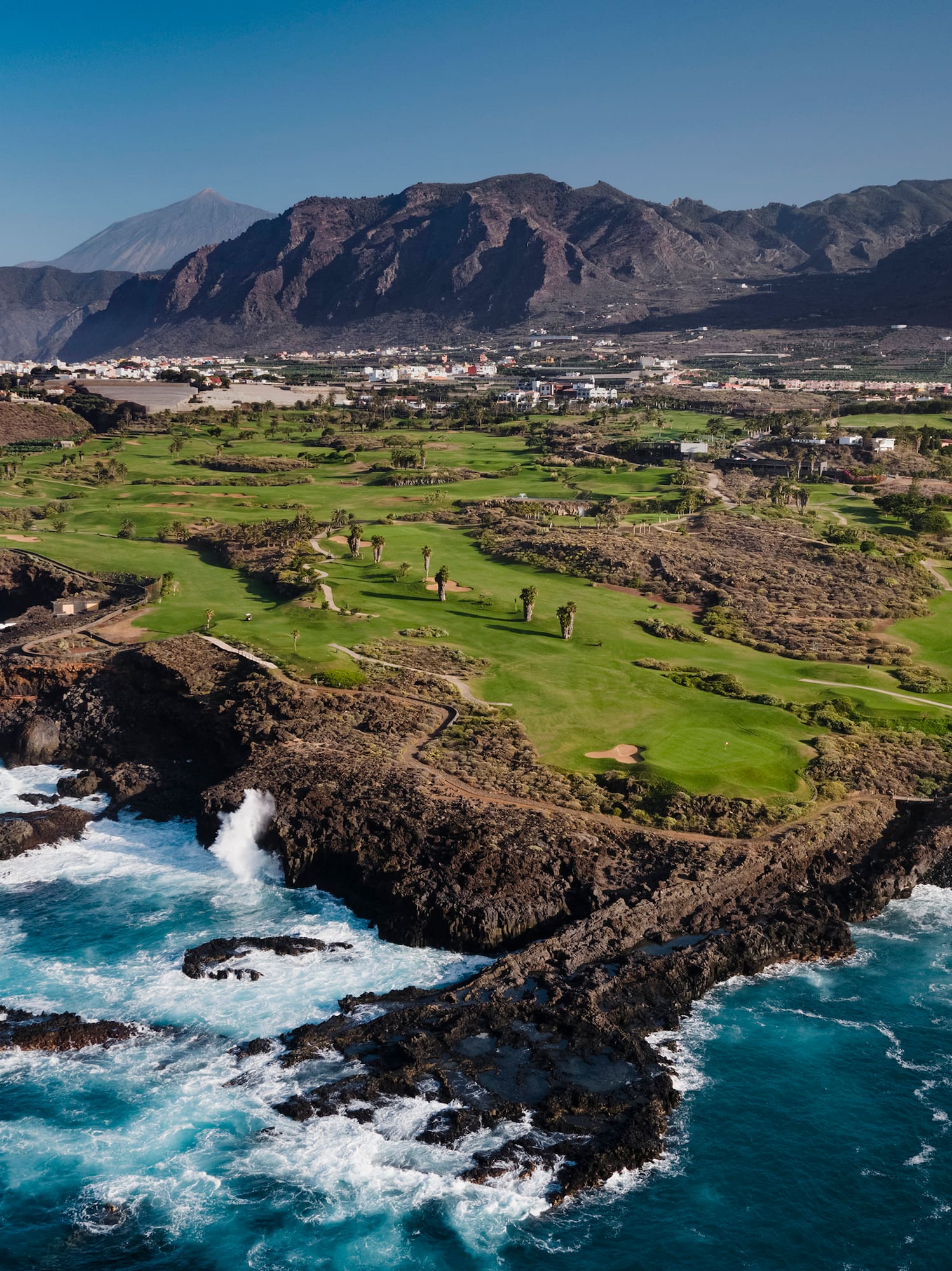 a golf course with a body of water and mountains in the background