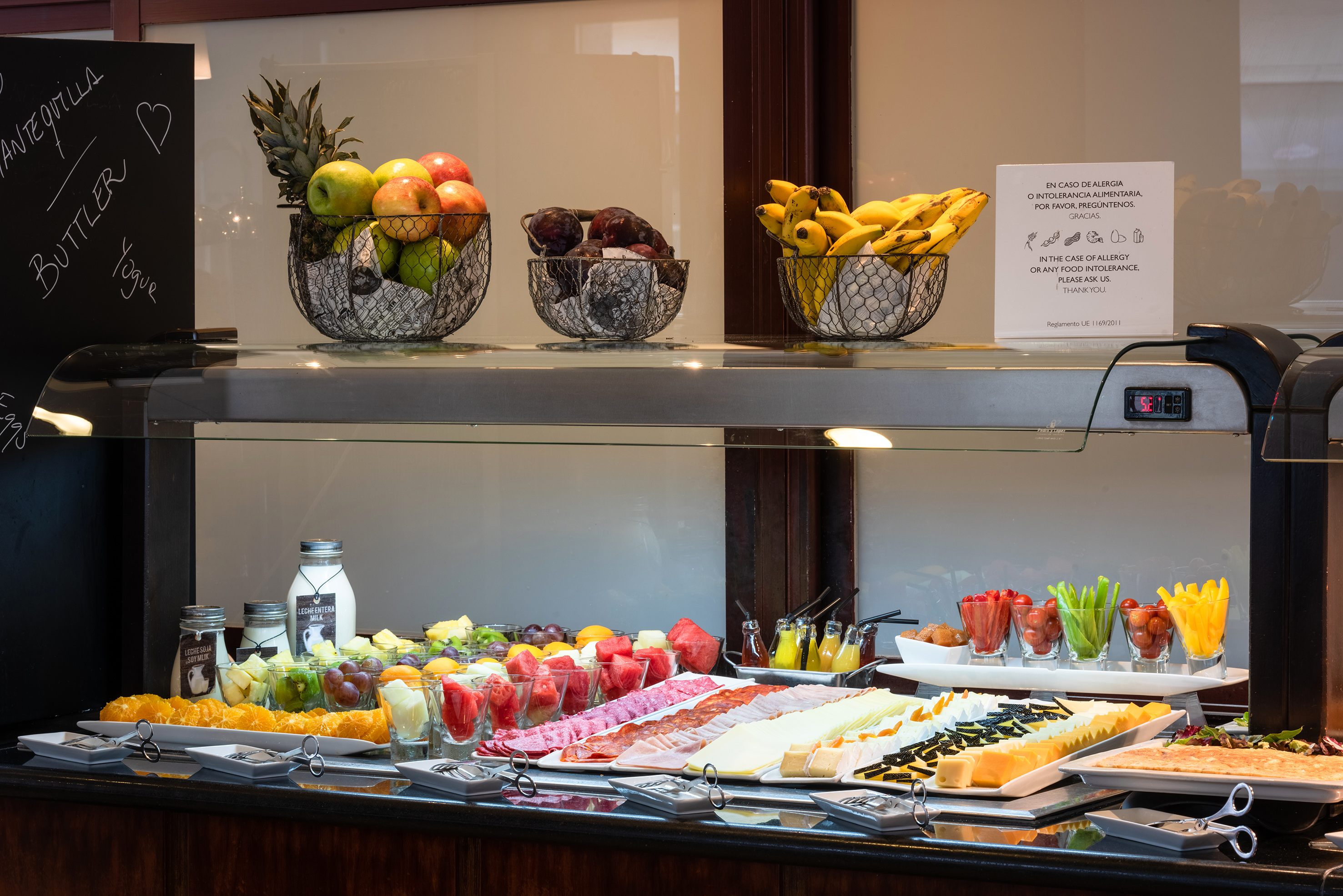 Extensive breakfast buffet display with fresh fruit, cheeses, and cold cuts.