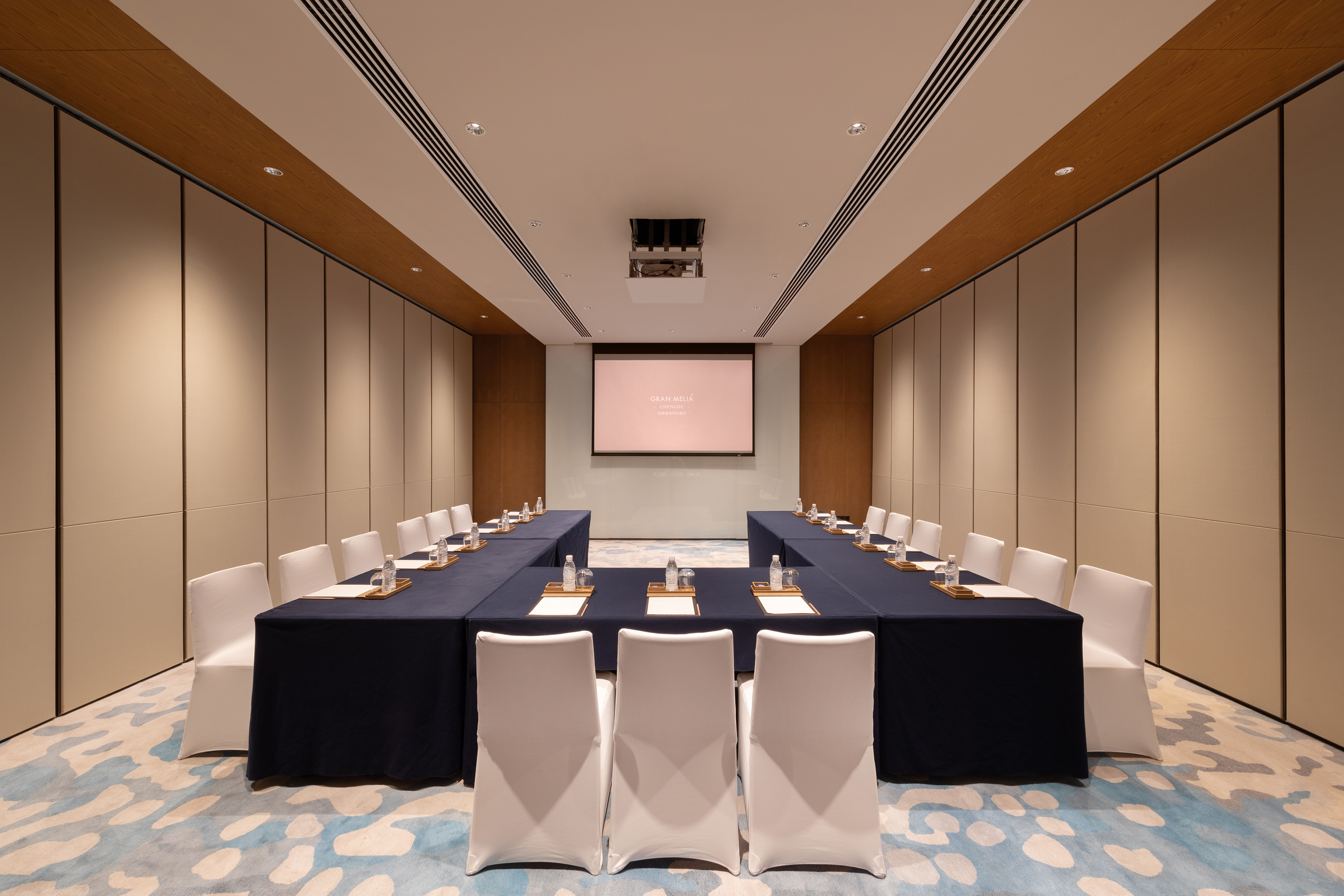 Modern U-shape conference room with projector screen, white chairs. Gran Meliá hotel.