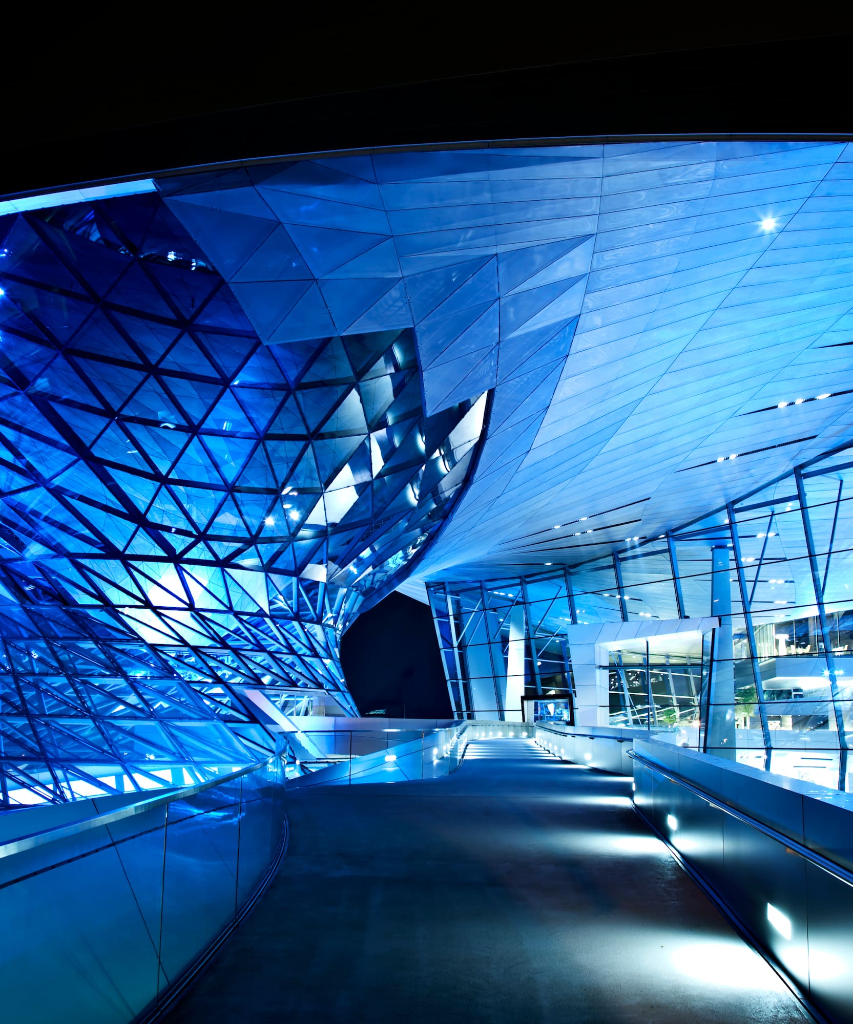 Arquitectura moderna de vidrio y metal azul en la noche, BMW Welt Múnich.