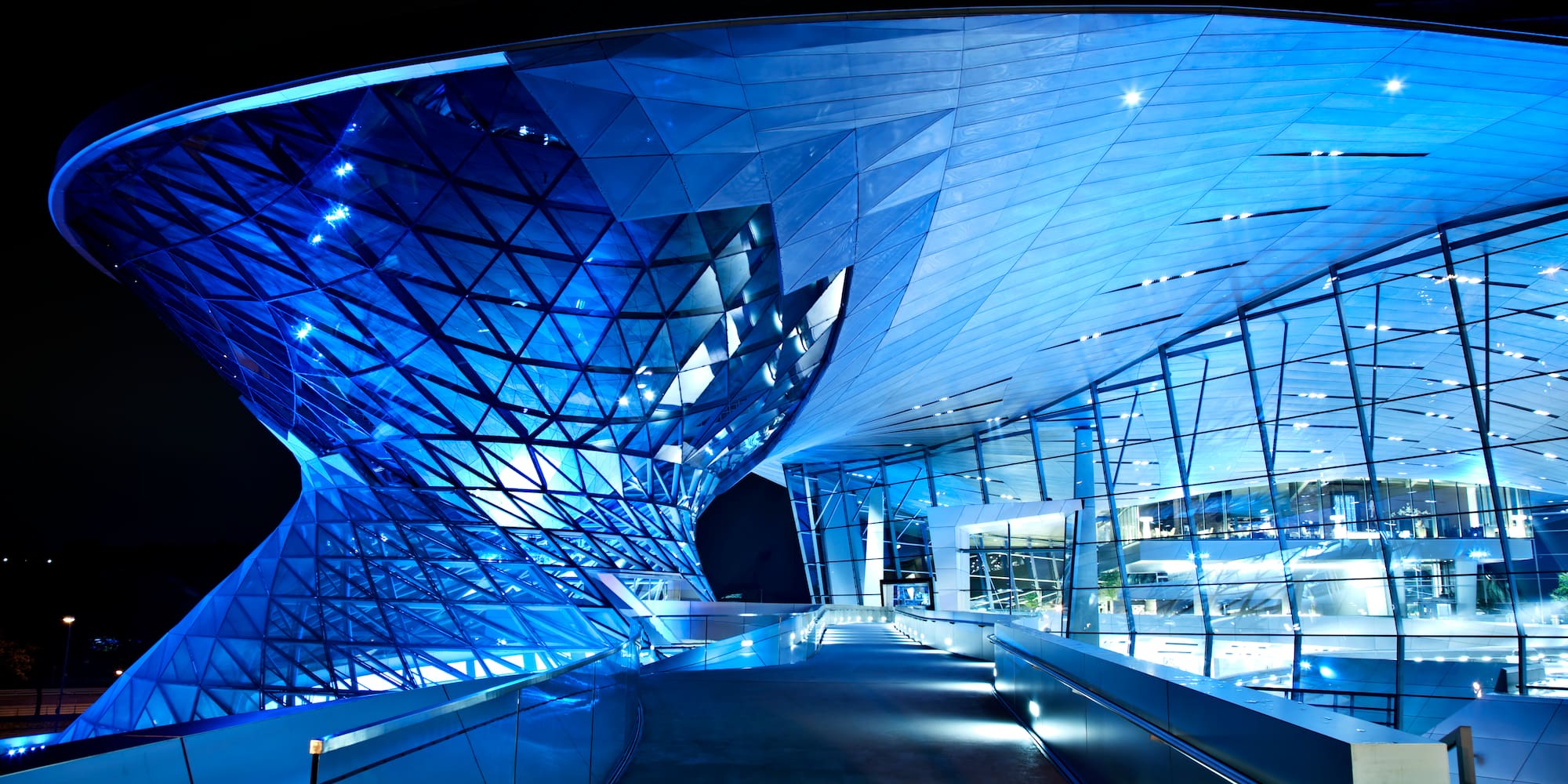 BMW Welt, Munich: futuristic architecture with blue glass facade at night.