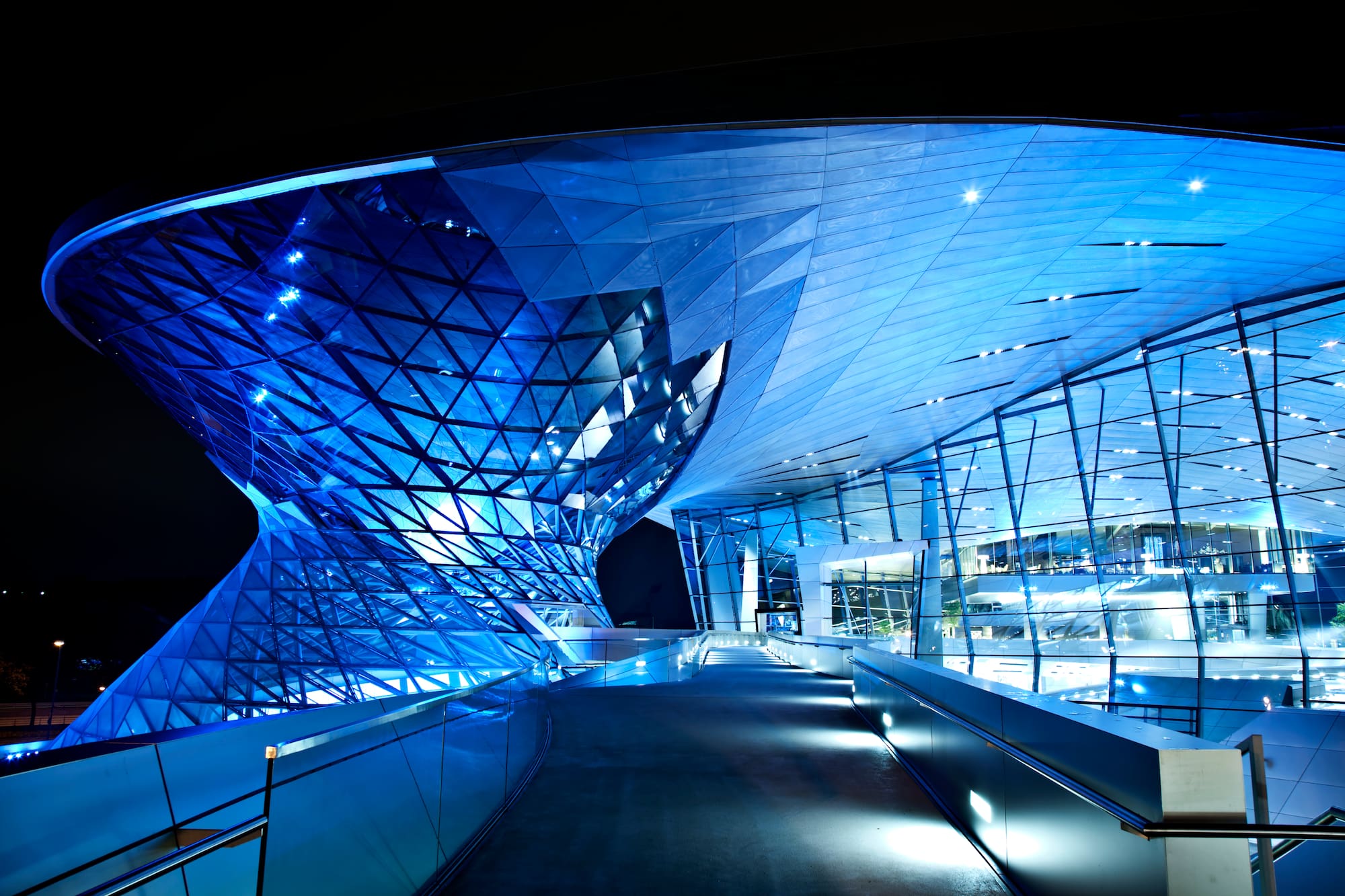 Arquitectura moderna de vidrio y metal azul en la noche, BMW Welt Múnich.