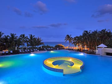 a pool with a circular pool with lights and palm trees