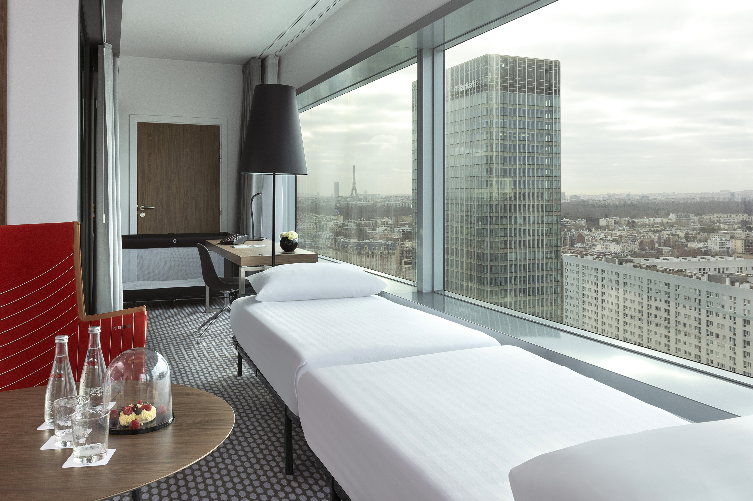 Modern hotel room with panoramic Paris city view and Eiffel Tower.