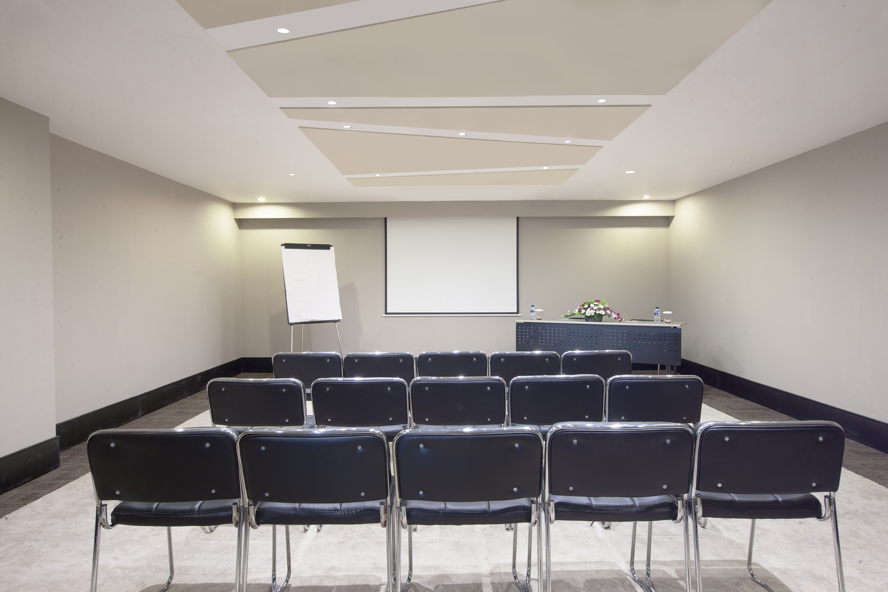 Empty conference room with chairs, projector screen, and flipchart.