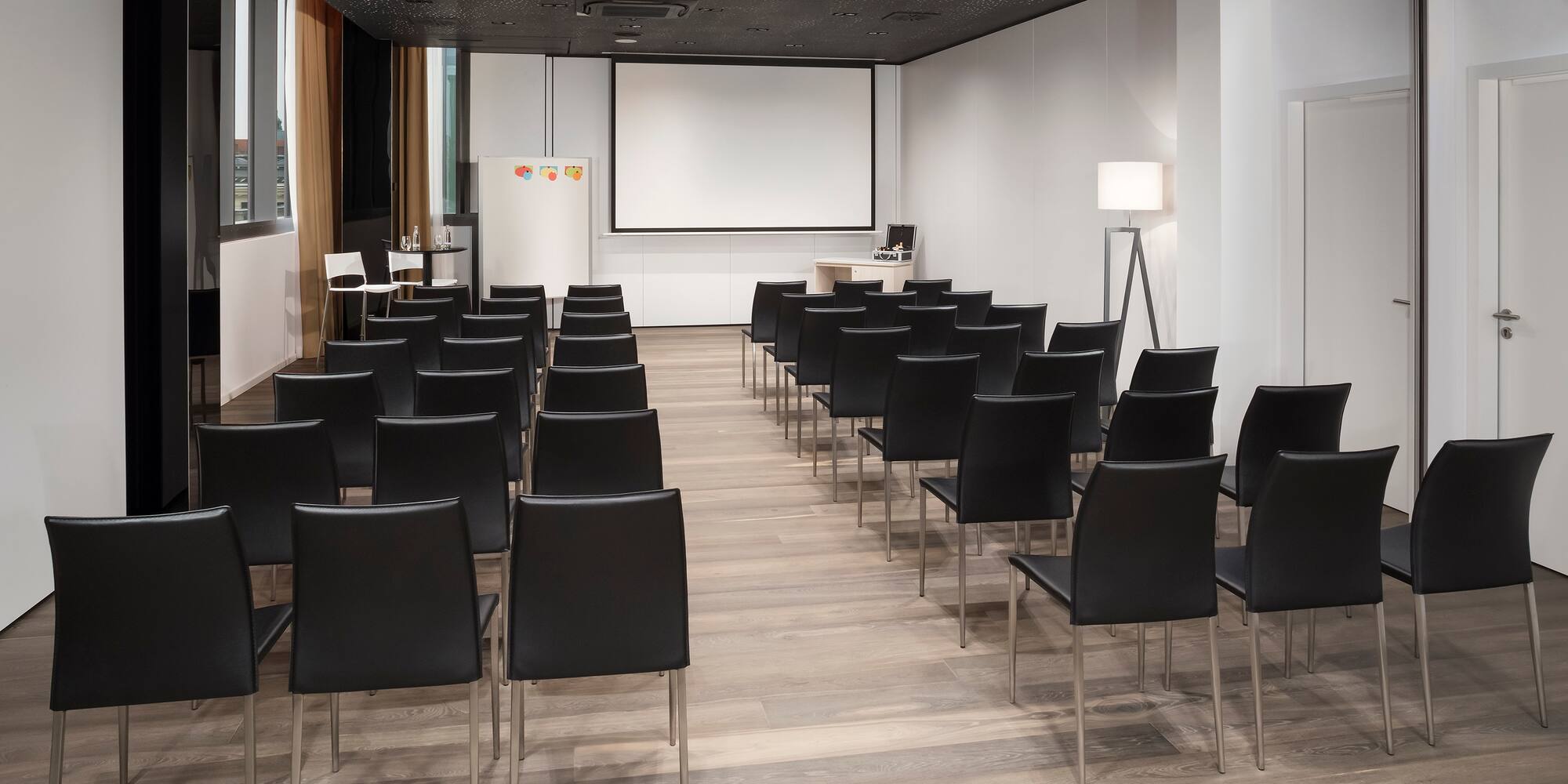 a room with black chairs and a projector screen