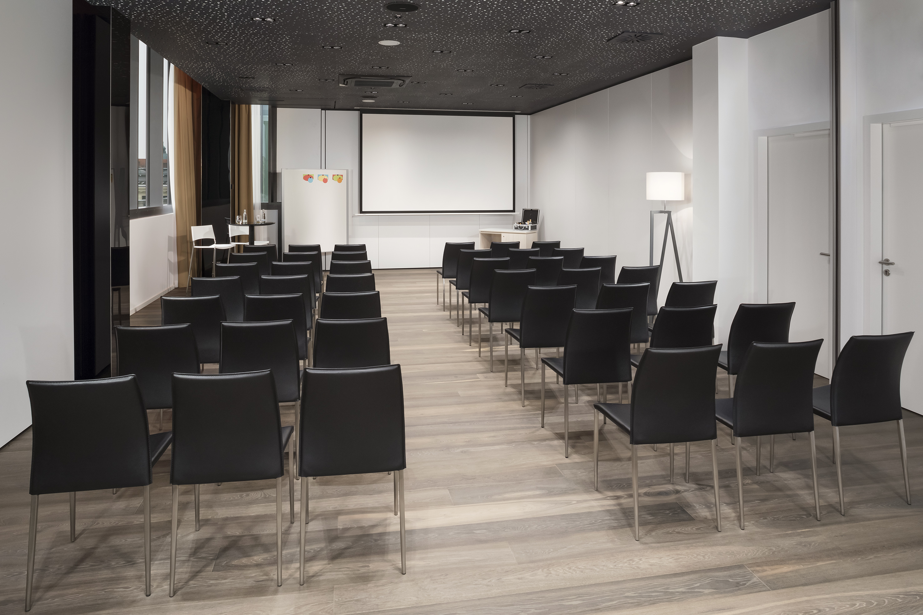 a room with black chairs and a projector screen