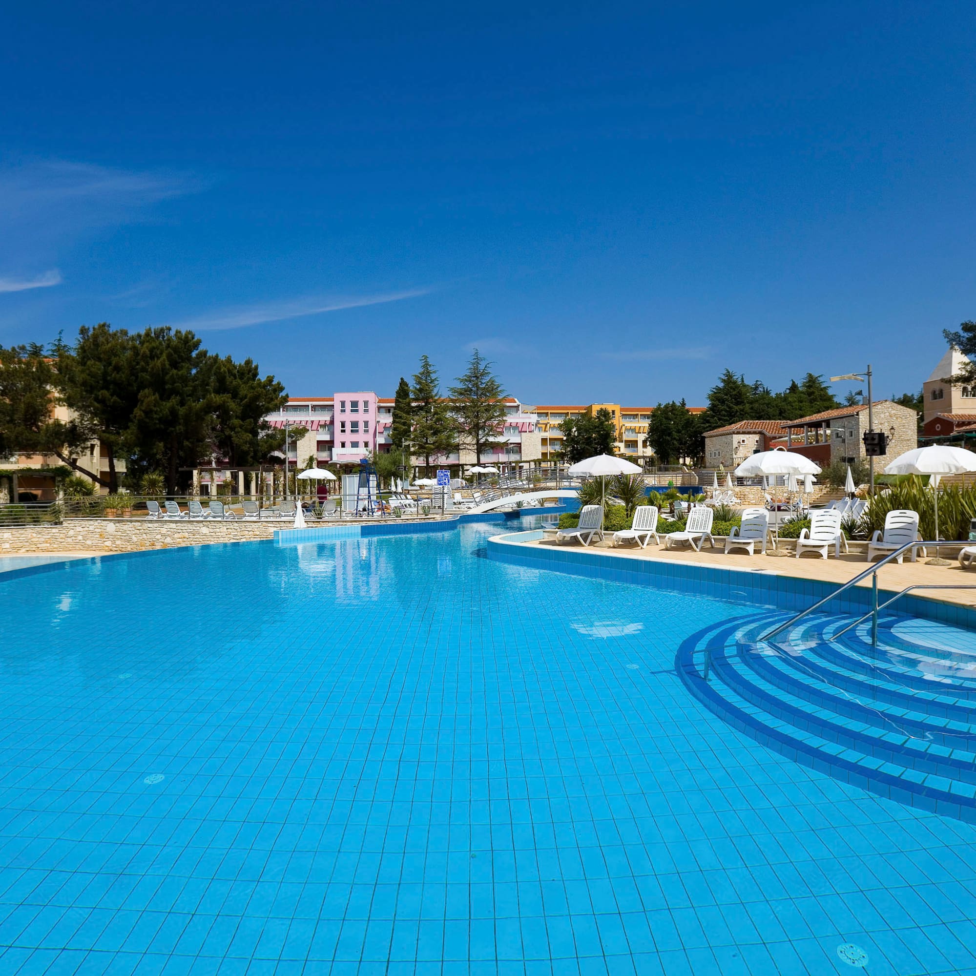 a swimming pool with chairs and umbrellas