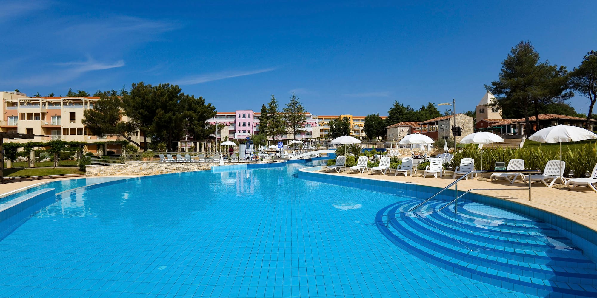 a swimming pool with chairs and umbrellas