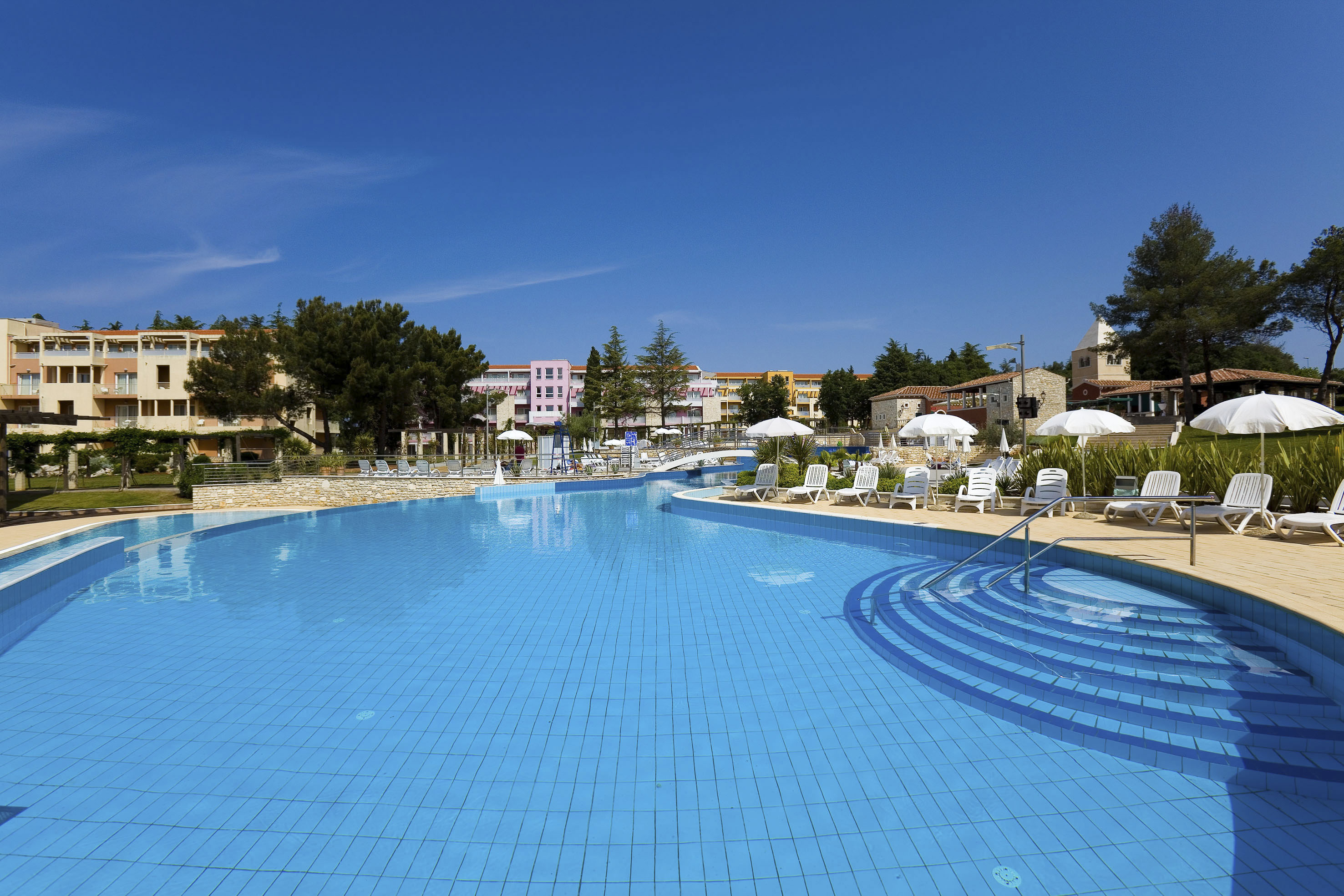 a swimming pool with chairs and umbrellas