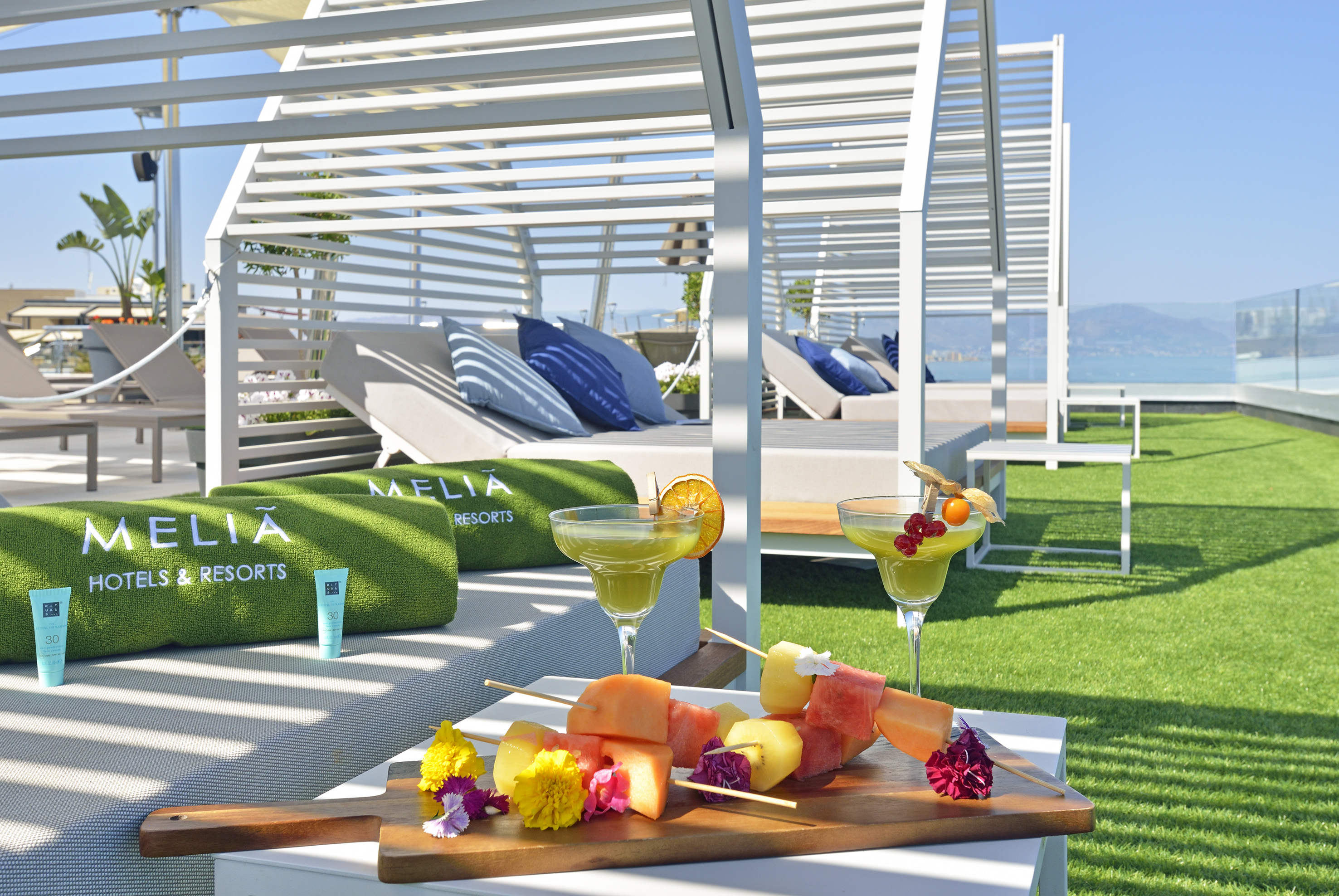 a tray of fruit and drinks on a table by a beach